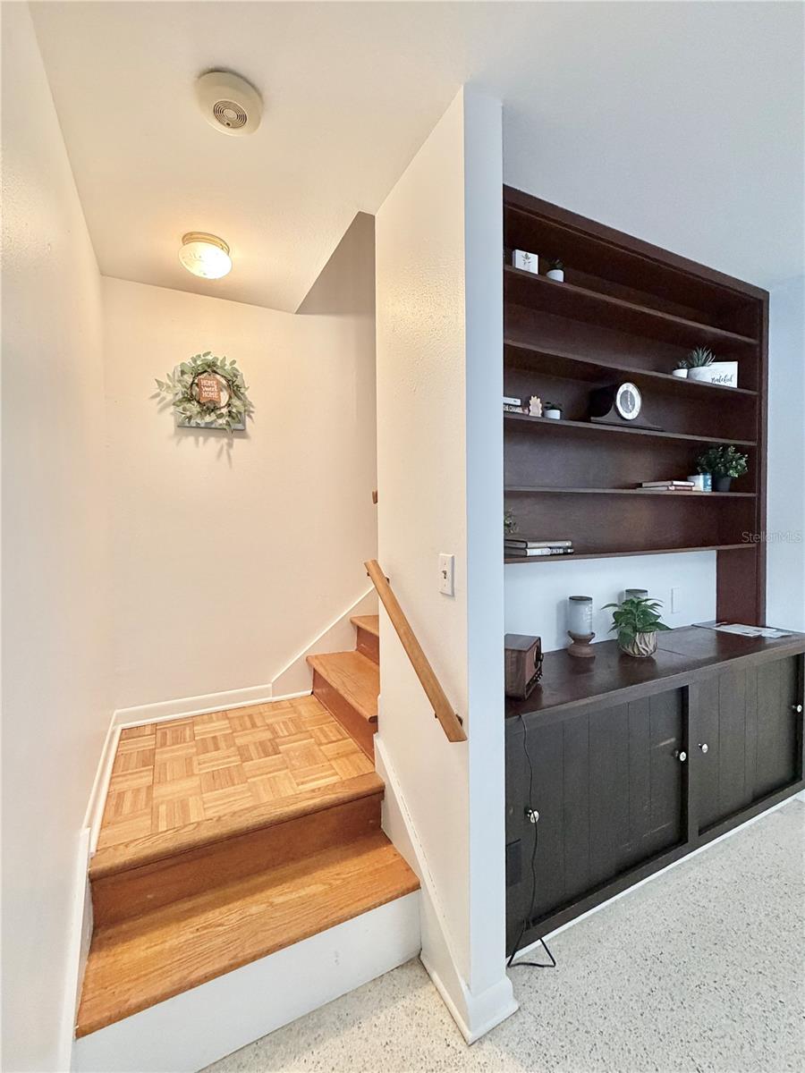 Living Room has built-in shelving and overlooks the pool through a large window.
