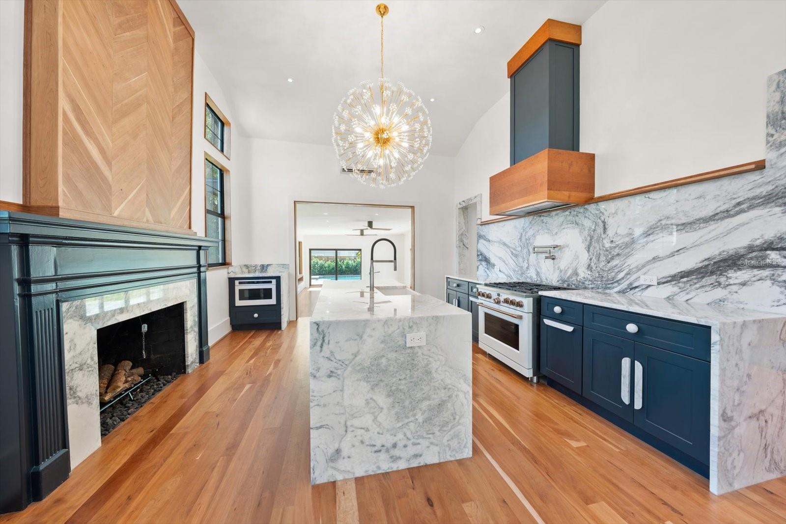 Chef's kitchen with marble waterfall island, fireplace, GE Café appliances, solid wood cabinets with soft close and roll out features.  Fireplace mantle is original to the home