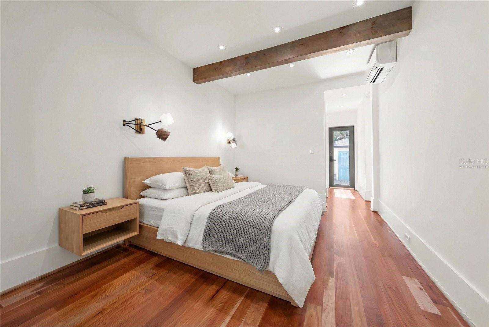 Primary bedroom with beamed ceiling, wall sconces, and door to backyard.  Virtually staged