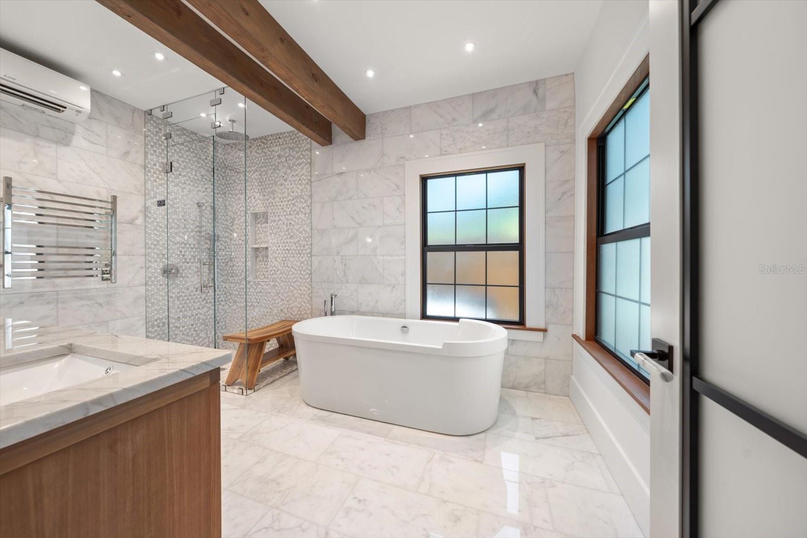 Primary en suite bath, Duravit soaking tub, zero entry glass shower, LED mirror, towel warmer, wood beam ceiling