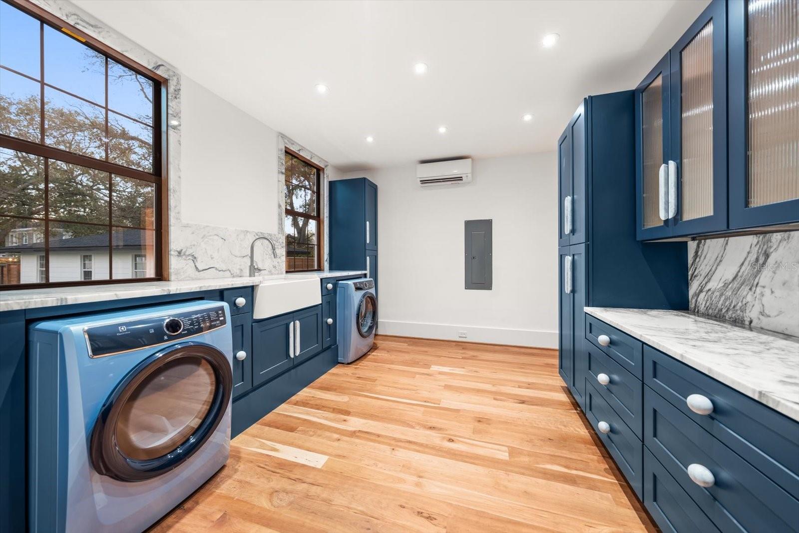 Scullery/laundry room with an abundance of solid wood cabinetry, apron front farmhouse sink, marble countertops, Electrolux washer & dryer.  Large windows overlooking backyard pool area