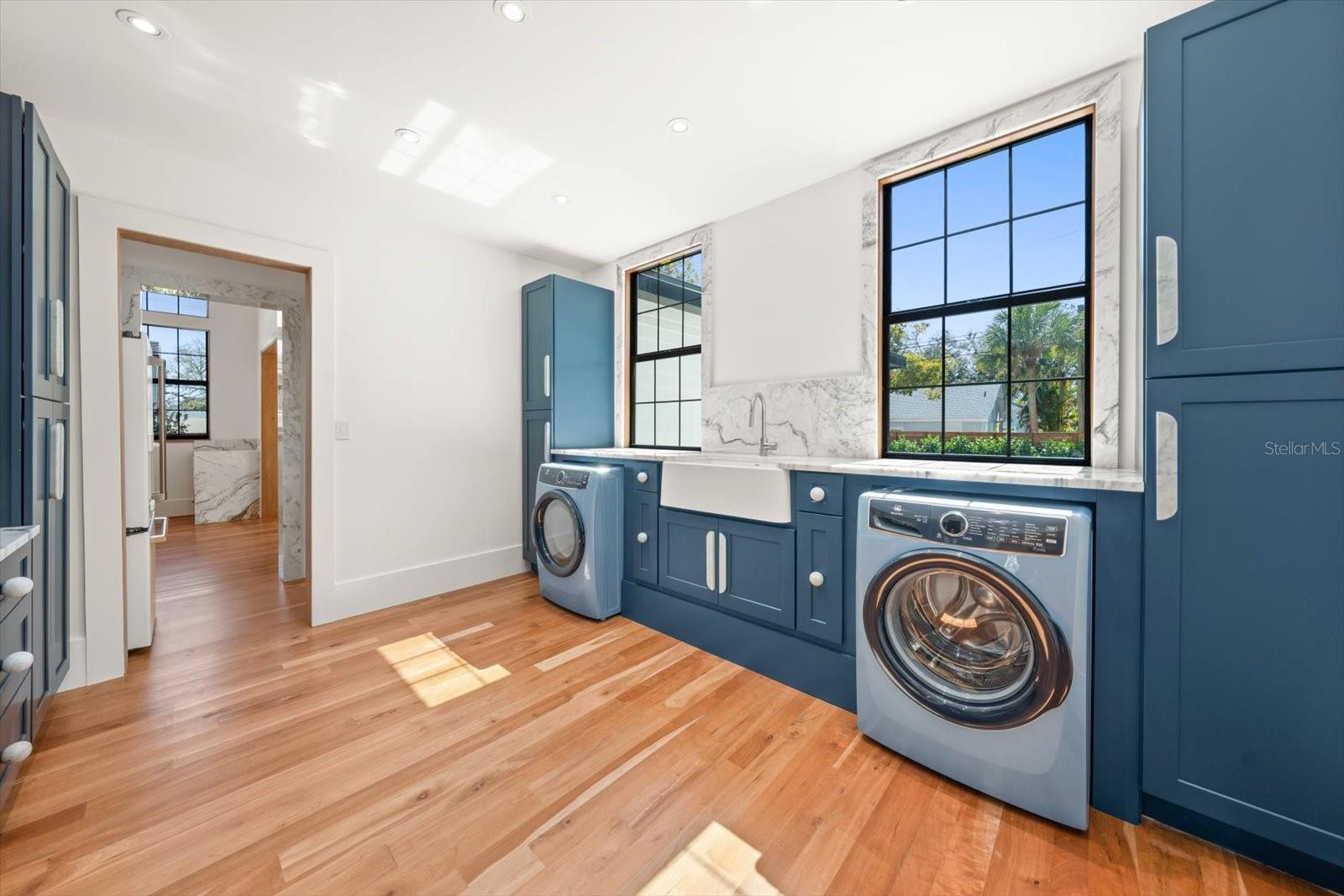 Scullery/laundry room access from kitchen with an abundance of solid wood cabinetry, apron front farmhouse sink, marble countertops, Electrolux washer & dryer.  Large windows overlooking backyard pool area