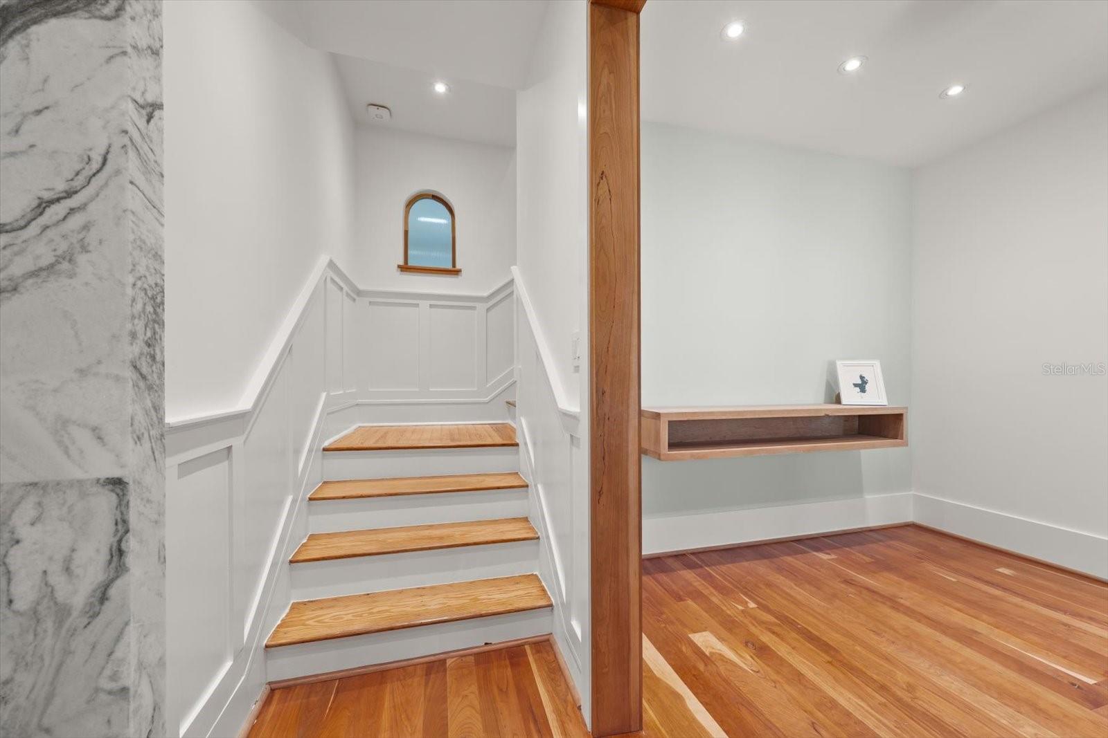 Stairs to second floor, original wood flooring and railings.  Window looks into scullery/laundry. Foyer with floating shelves