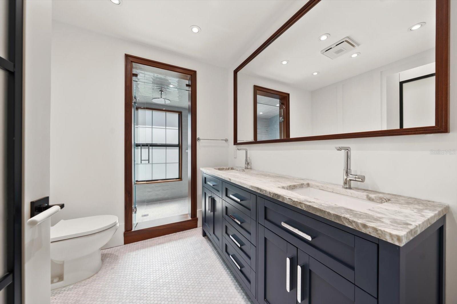 Hall bath with dual sinks, beautiful shower, solid wood cabinetry with organizational compartments built in the drawers, leathered granite countertop