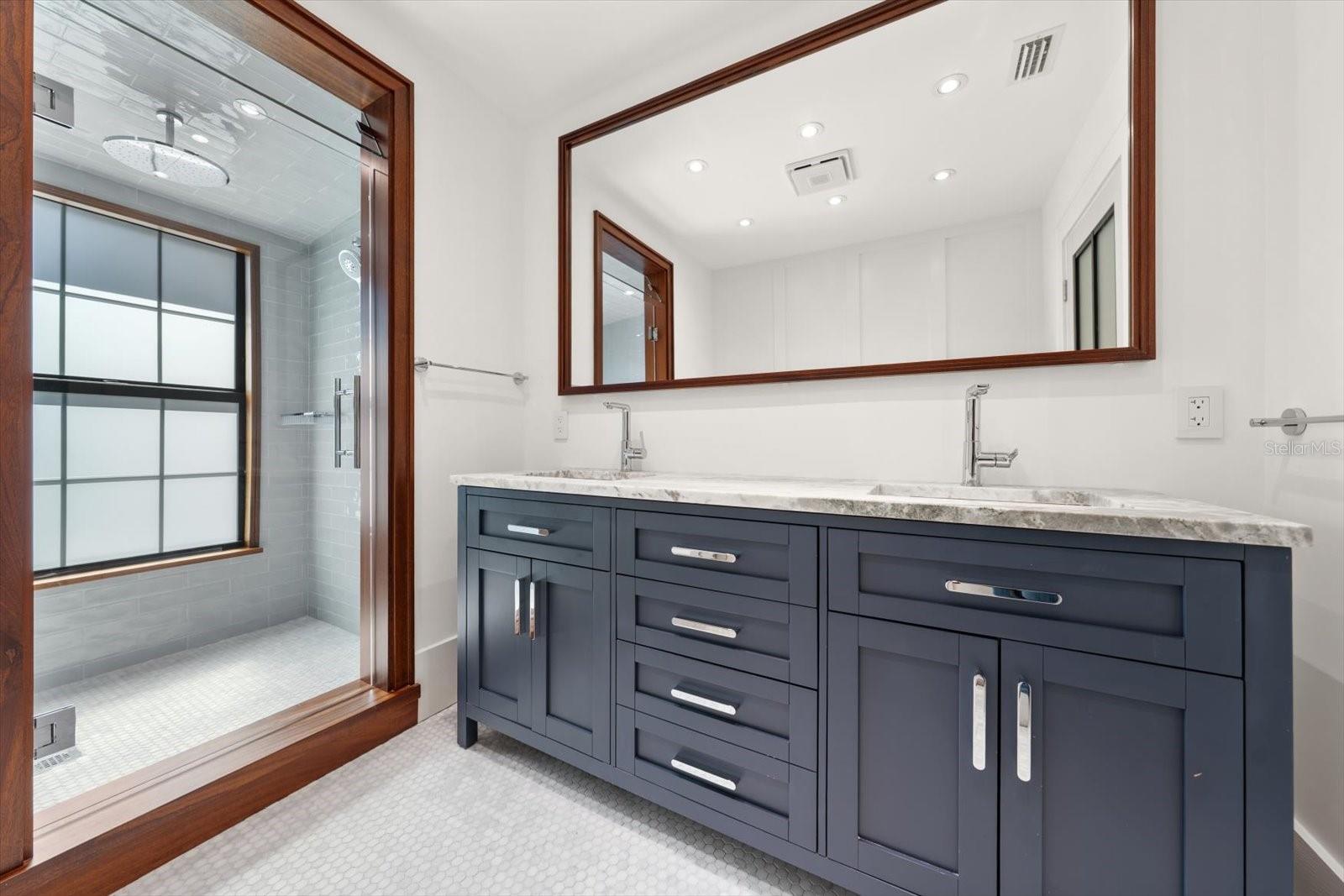 Hall bath with dual sinks, beautiful shower with rain head, solid wood cabinetry with organizational compartments built in the drawers, leathered granite countertop