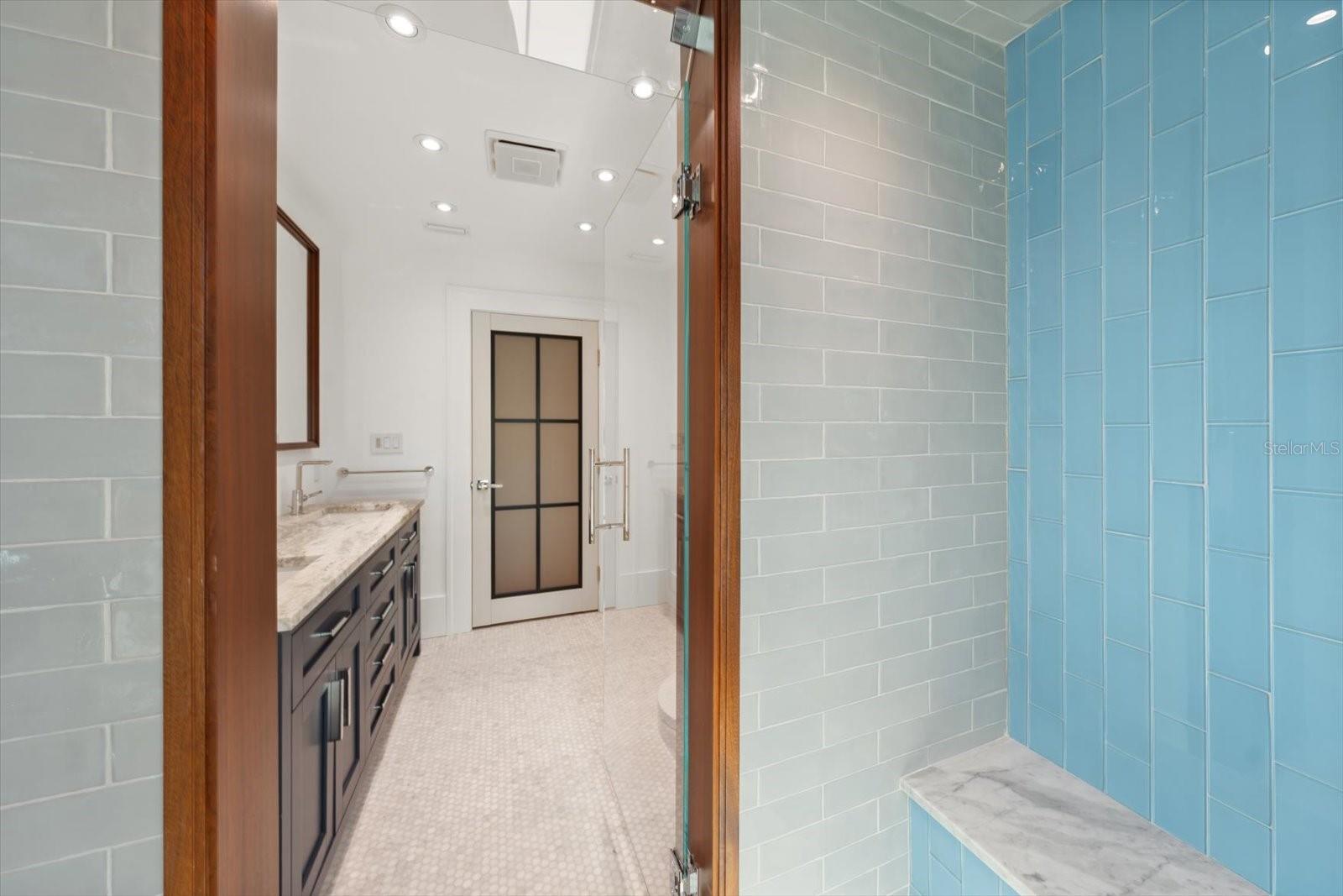 Hall bath with dual sinks, beautiful shower with glass tile, all wood framing is mahogany, built in shower seat, solid wood cabinetry with organizational compartments built in the drawers, leathered granite countertop