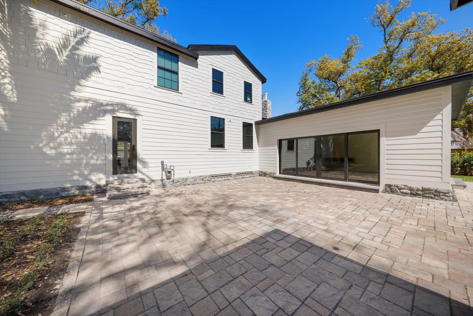 Expansive brick paver backyard living/entertaining space. Surrounded by lush landscaping, lots of grass and beautiful 7' deep pool.