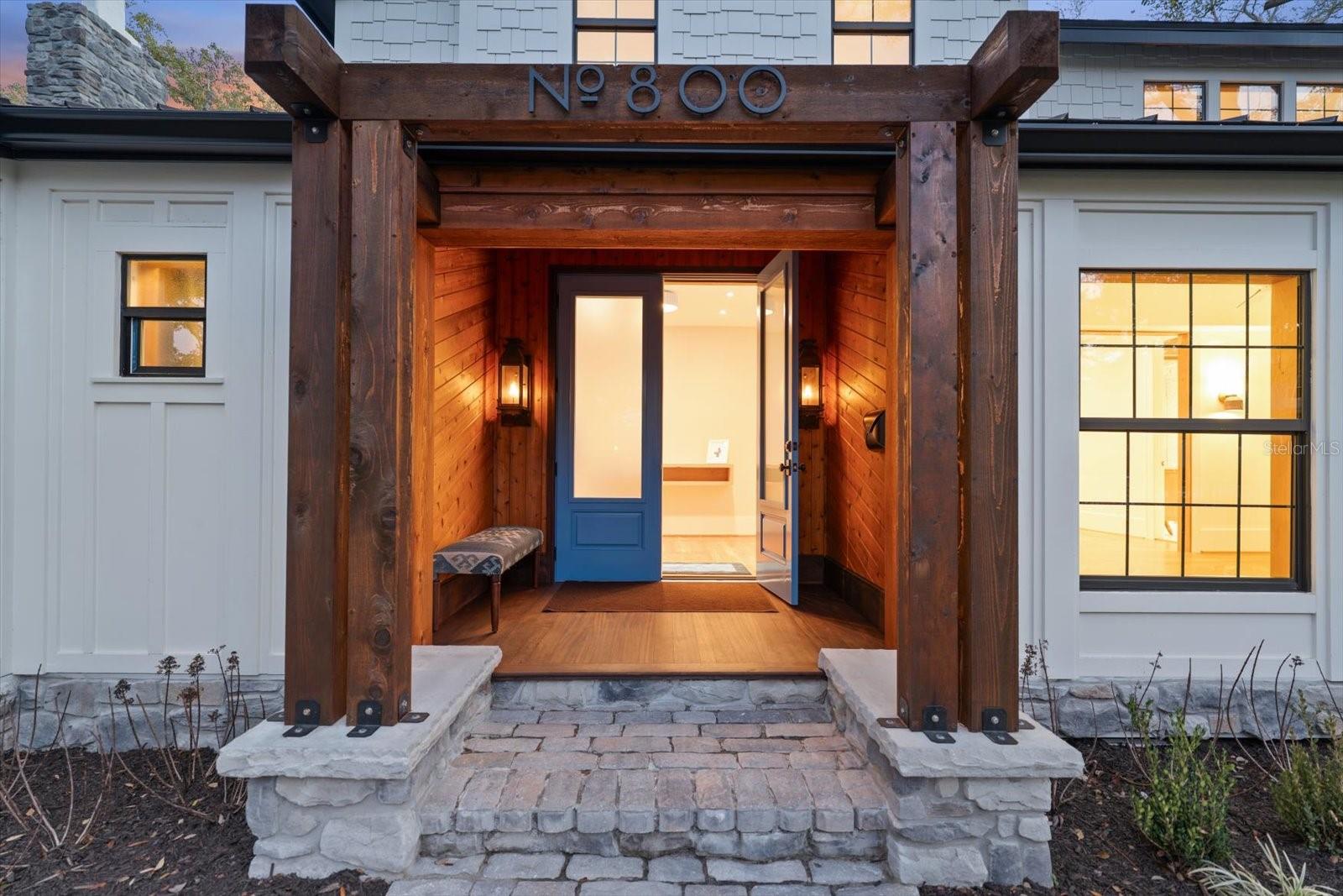 Front porch with cedar tongue & groove walls, mahogany floor, gas lanterns and stone walkway at twilight