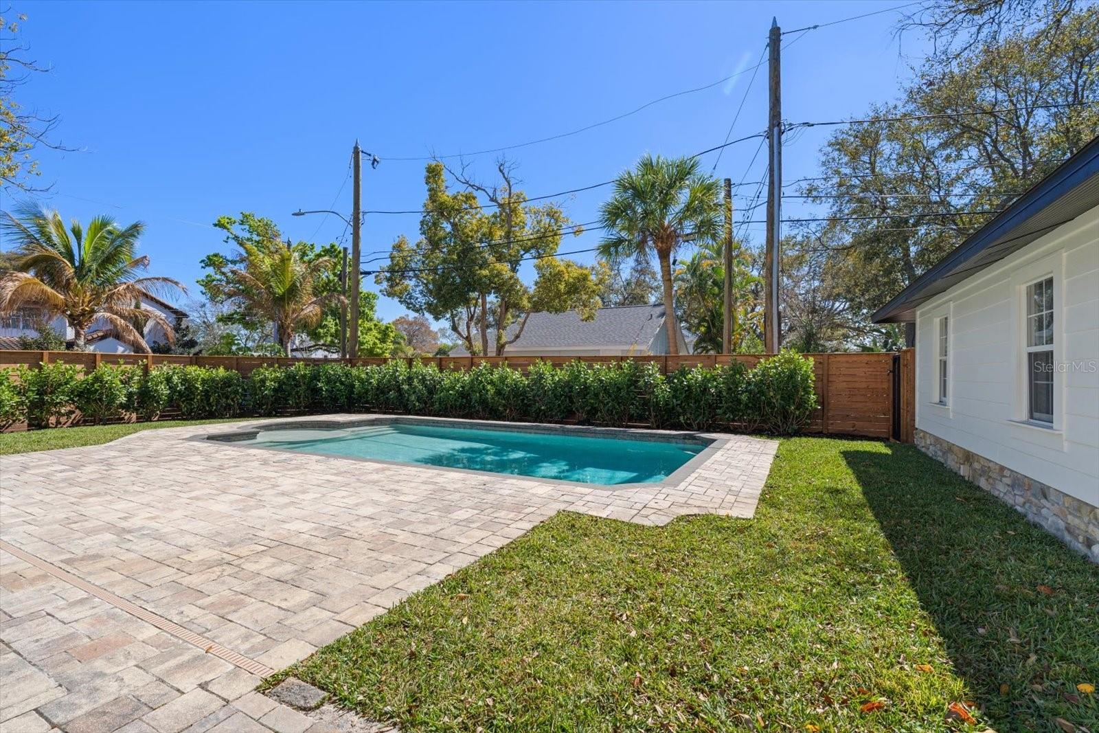 Expansive brick paver pool deck, surrounded by lush landscaping, lots of grass and beautiful 7' deep pool with sunshelf and lighting.  Oversized 2 car garage with alley access.