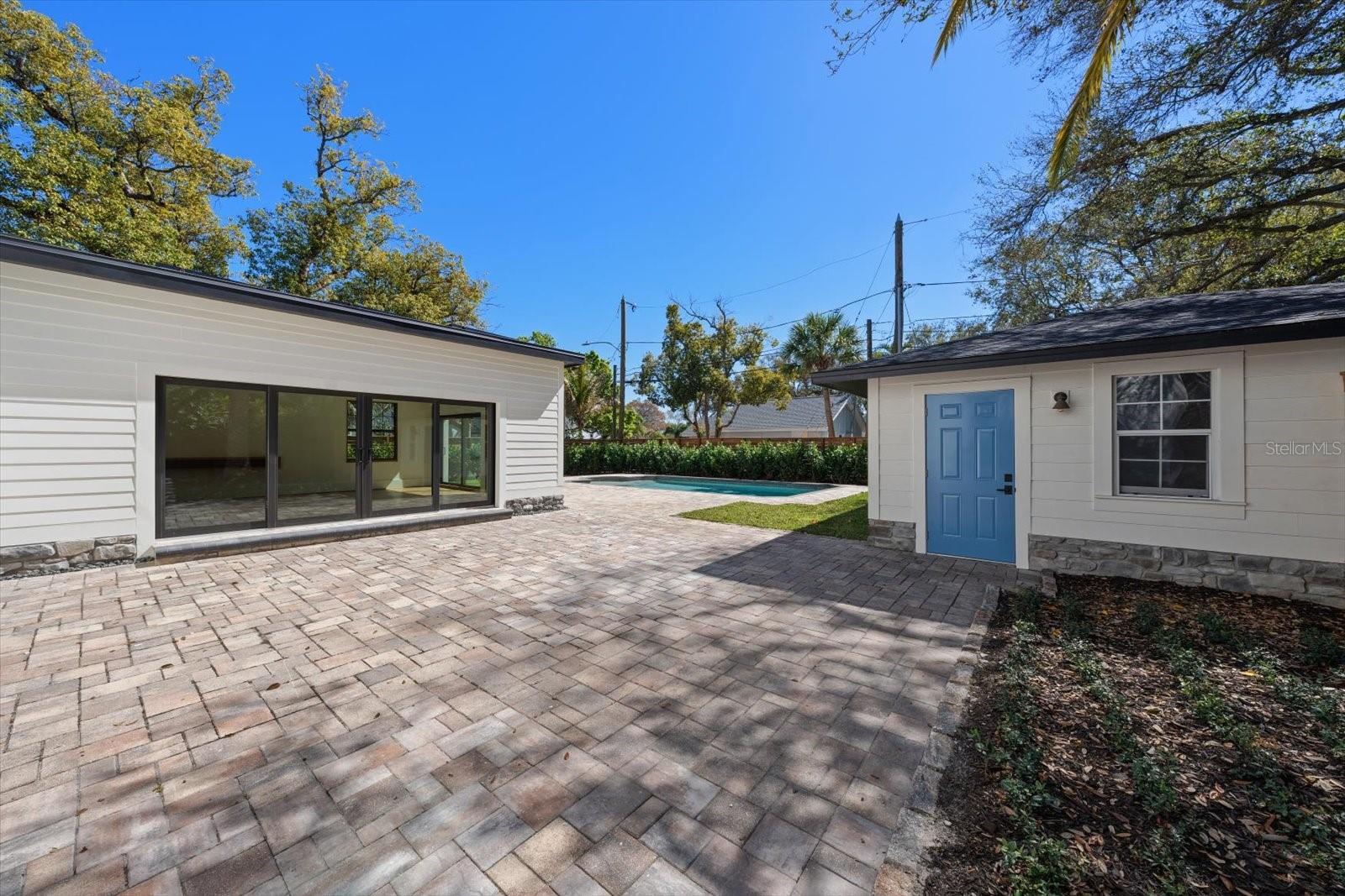 Pocketing sliding glass doors to expansive brick paver pool deck, outdoor living/entertaining space, surrounded by lush landscaping, lots of grass and beautiful 7' deep pool with sunshelf and lighting. Oversized 2 car garage with alley access.