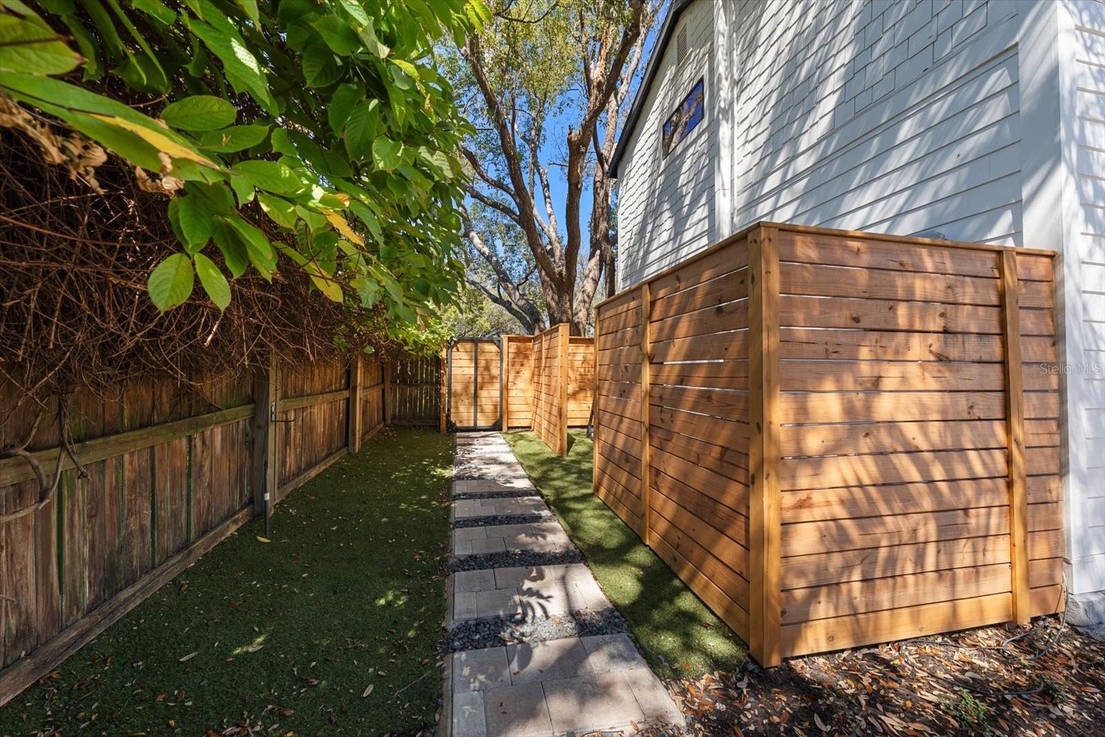 West side of home, fenced in equipment: A/C's, Rinnai tankless water heater, solar equipment.  Lush landscaping and lovely walkways.