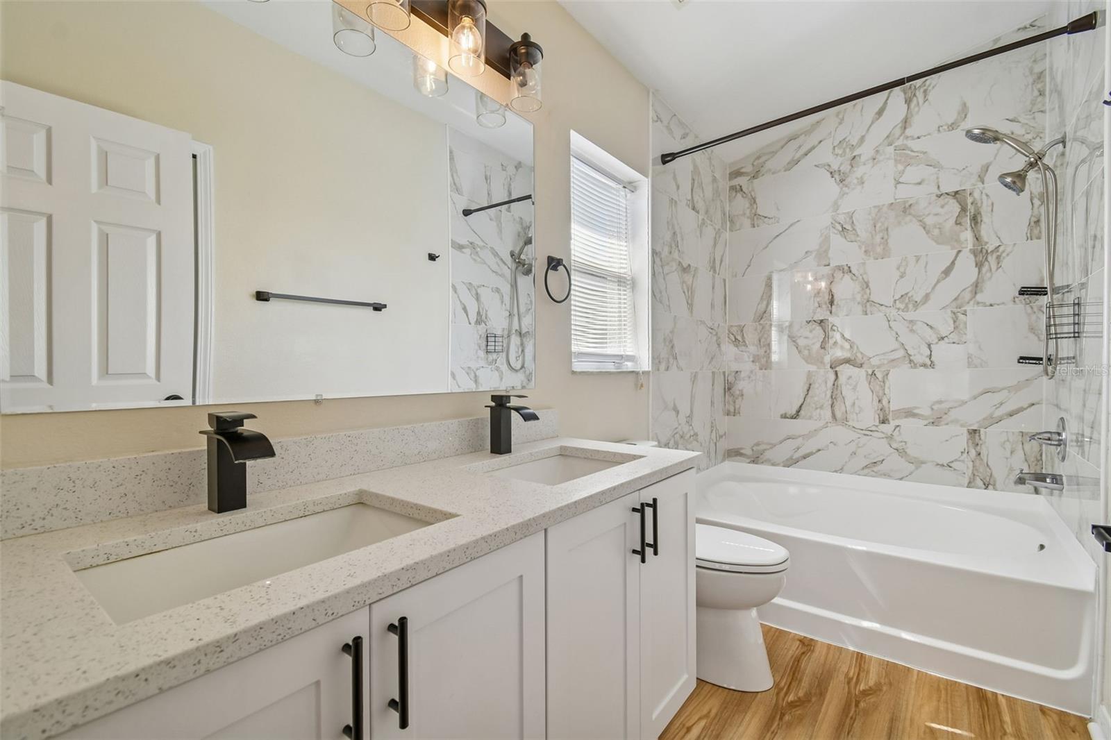 A fresh, spa inspired space with double sinks, modern lighting, and a beautifully tiled shower and tub for everyday comfort.