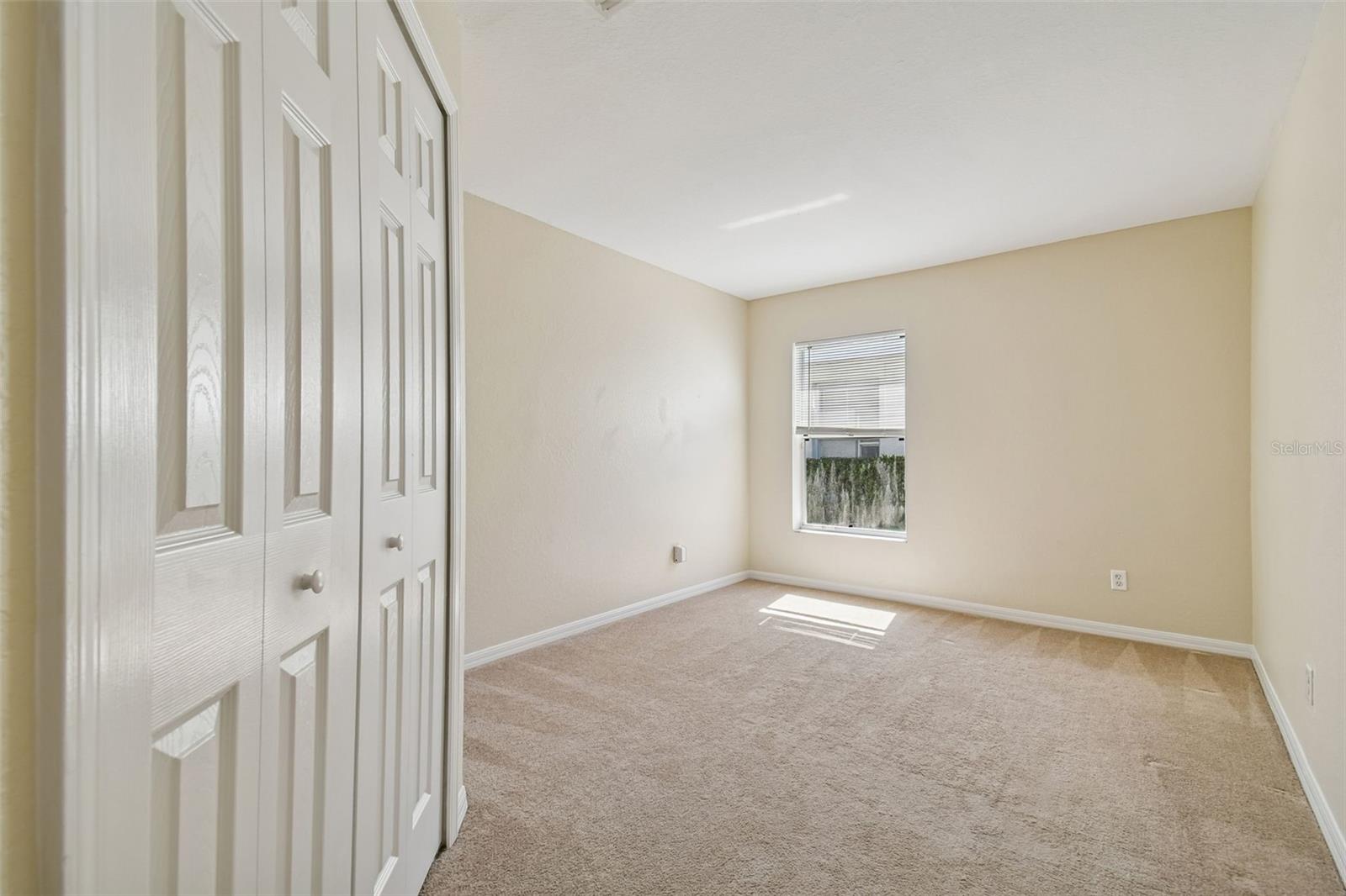 Bright and spacious third bedroom featuring soft neutral tones, plush carpeting, a large closet, and natural light from the window.