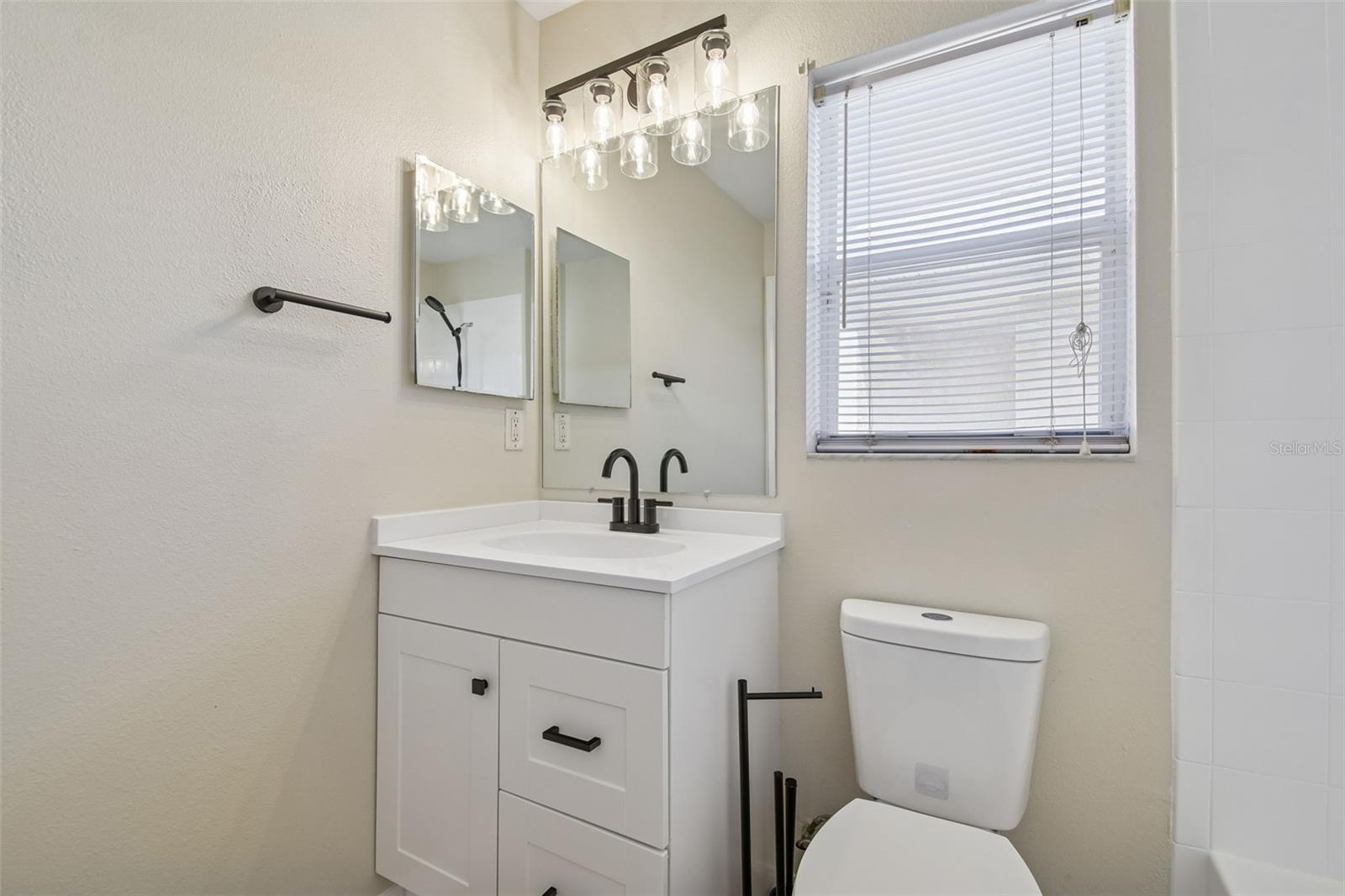 Stylish guest bath with updated vanity, matte black fixtures, and crisp finishes throughout.