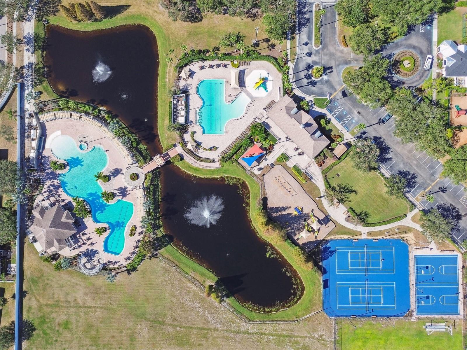 Aerial view showcasing multiple pools connected by scenic bridges over tranquil water features for a true resort inspired community experience.