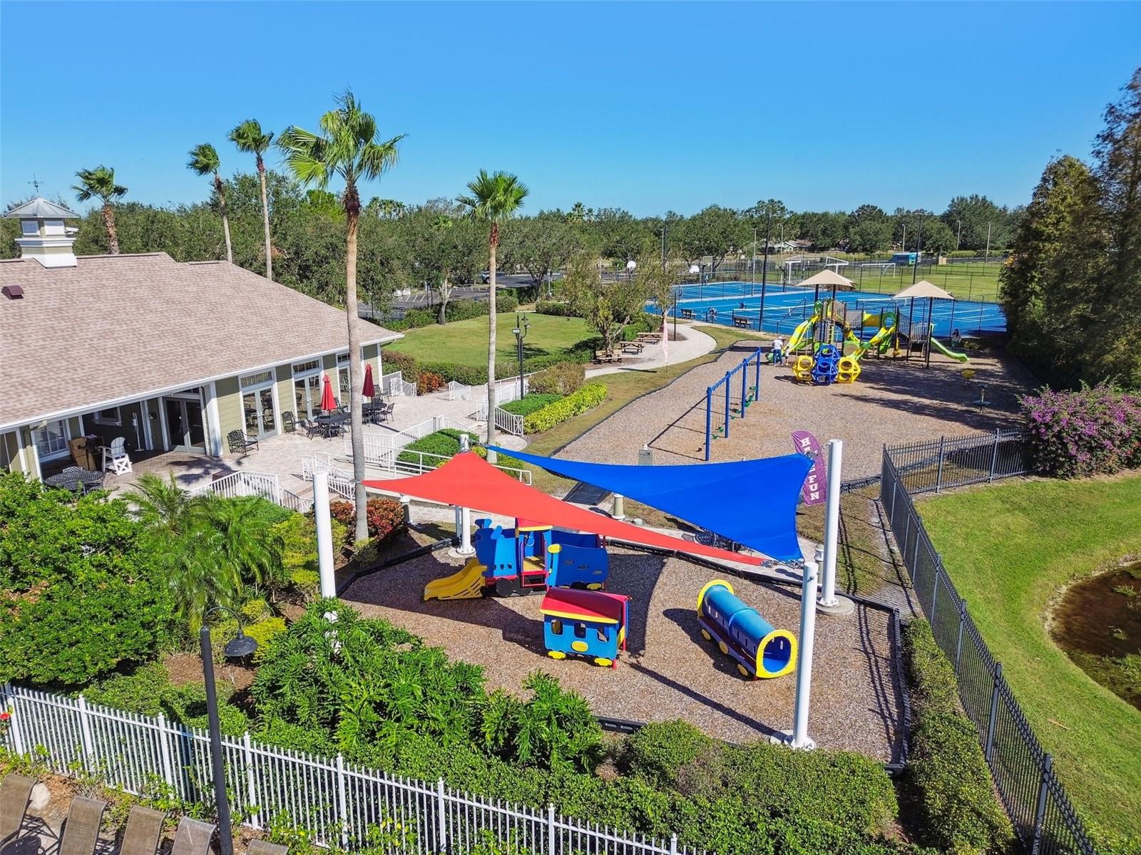 Shaded playground with colorful equipment provides a fun and safe space for outdoor play while parents enjoy nearby seating and green space.