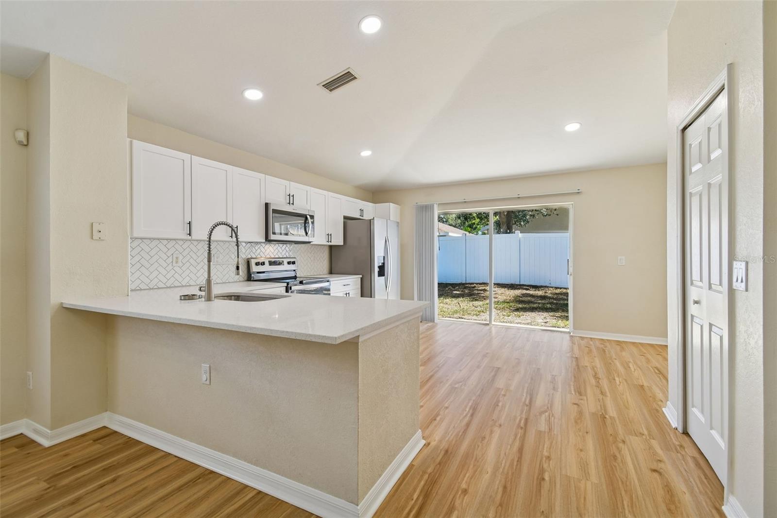 As you step inside, you’re greeted by a bright and airy open living and dining space filled with natural light, warm wood-look flooring, and clean, modern finishes.