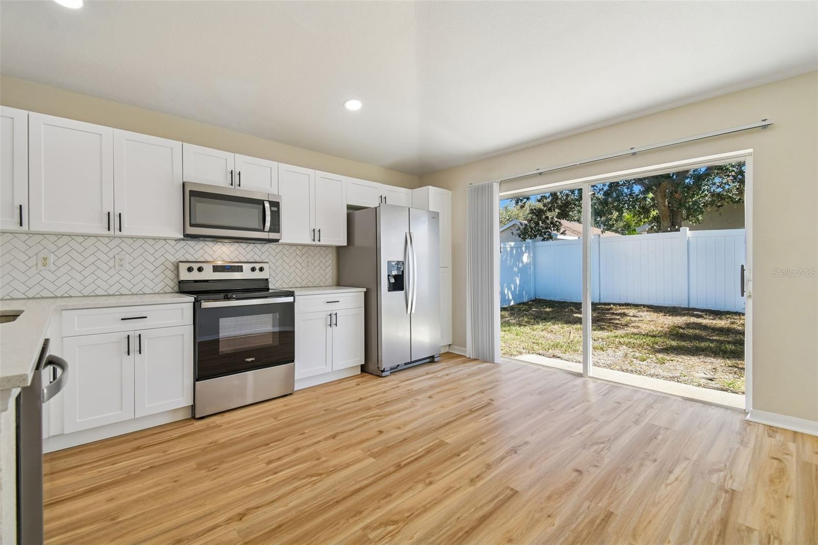 The generous living area offers plenty of room for gathering, with an open sightline to the kitchen and sliding glass doors that lead to the fully fenced backyard.