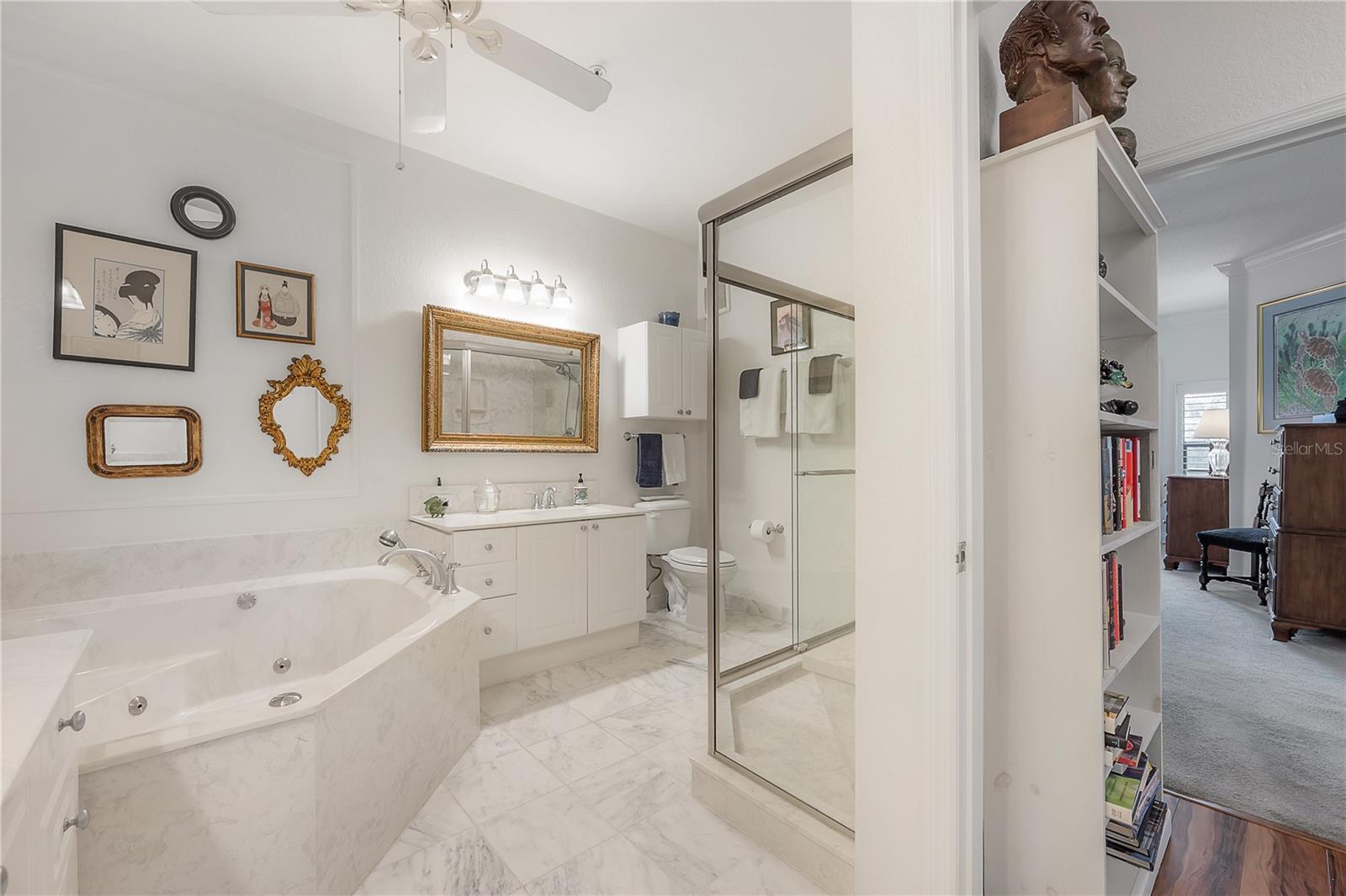 Bathroom with marble floors, jetted whirlpool tub, dual vanities, and walk-in shower