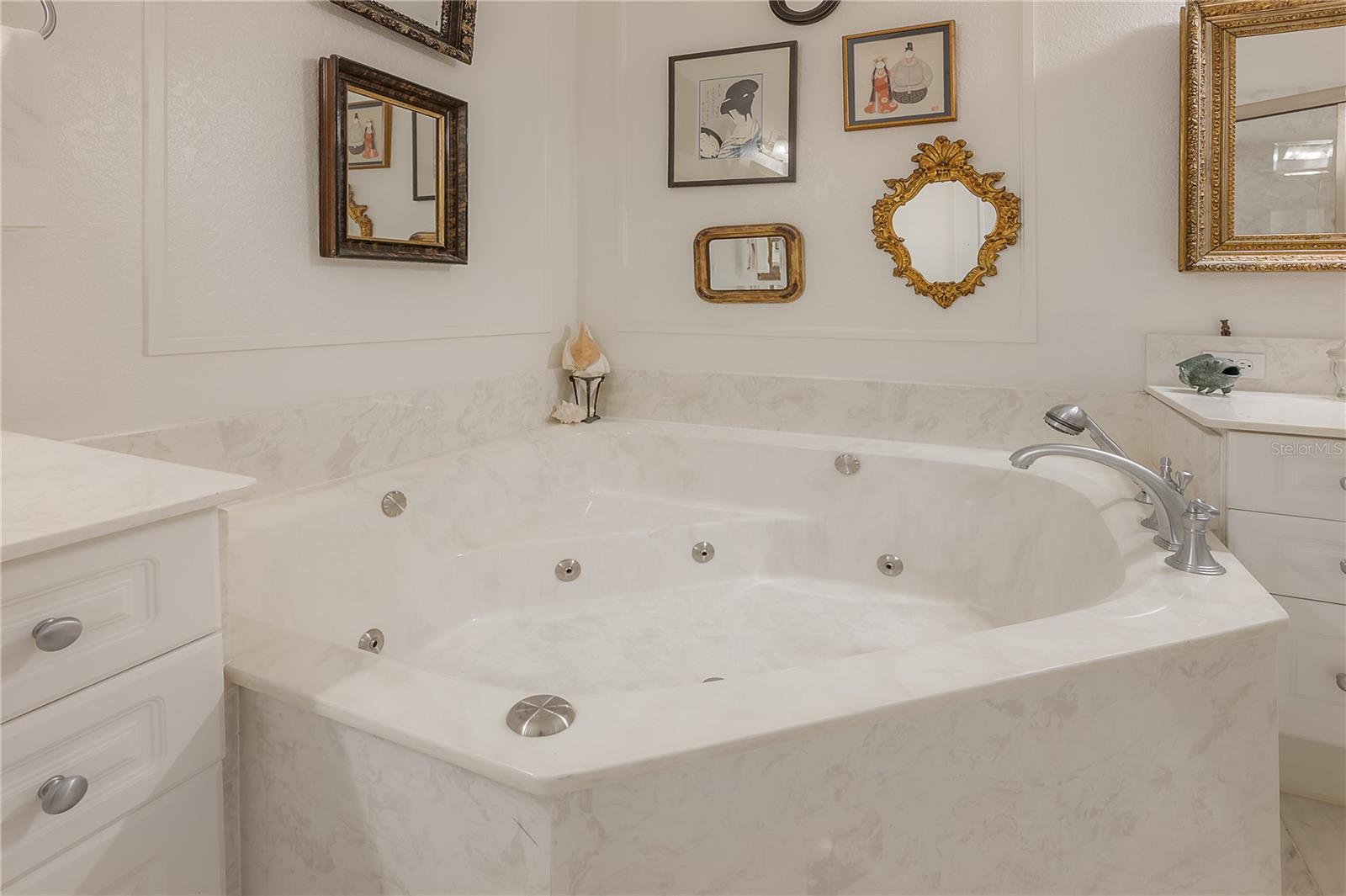 Bathroom with heated floors, dual vanities, marble flooring, jetted whirlpool tub, and and walk-in shower.