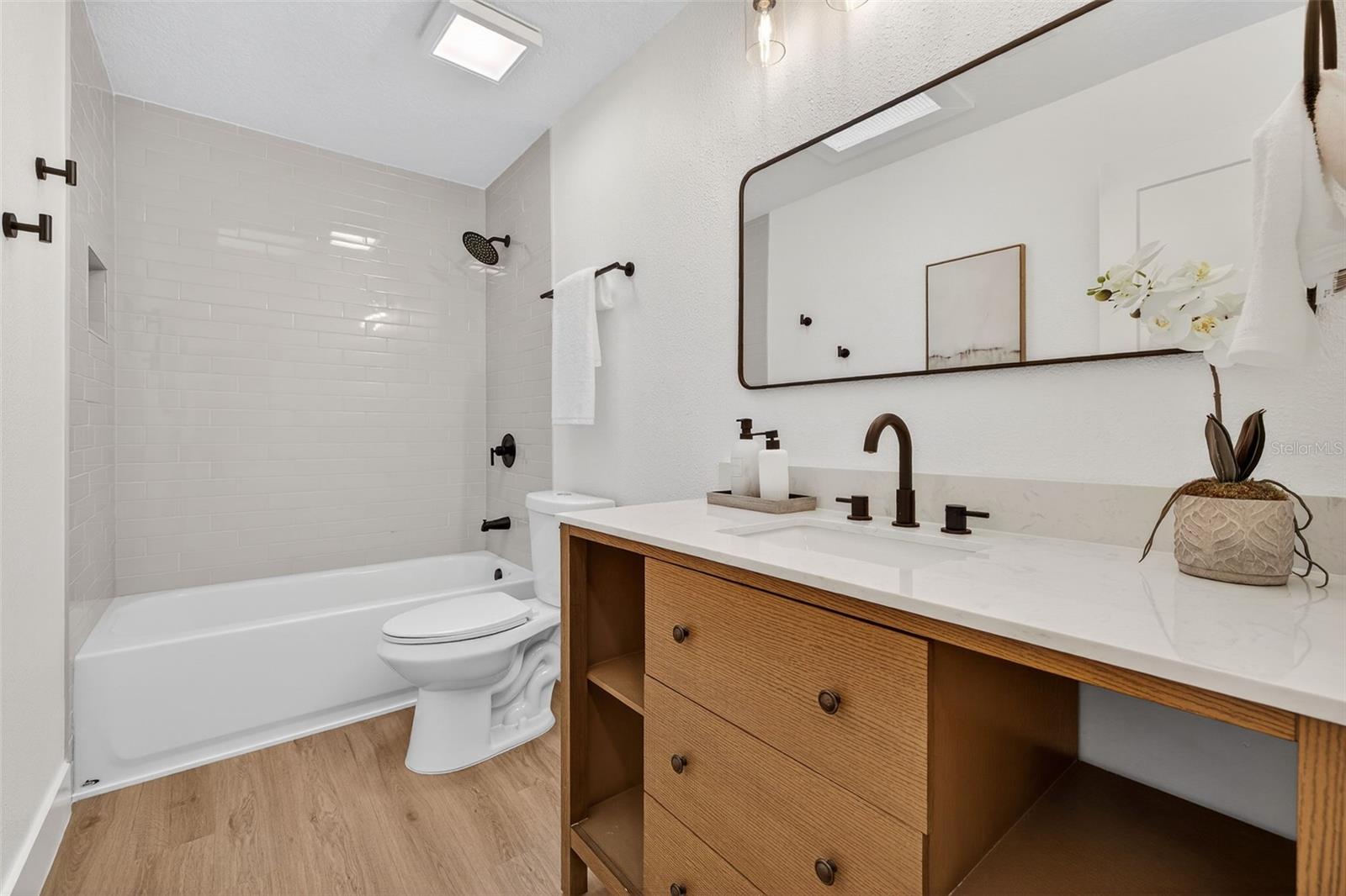 Updated vanity with sleek black fixtures and shower/tub combo