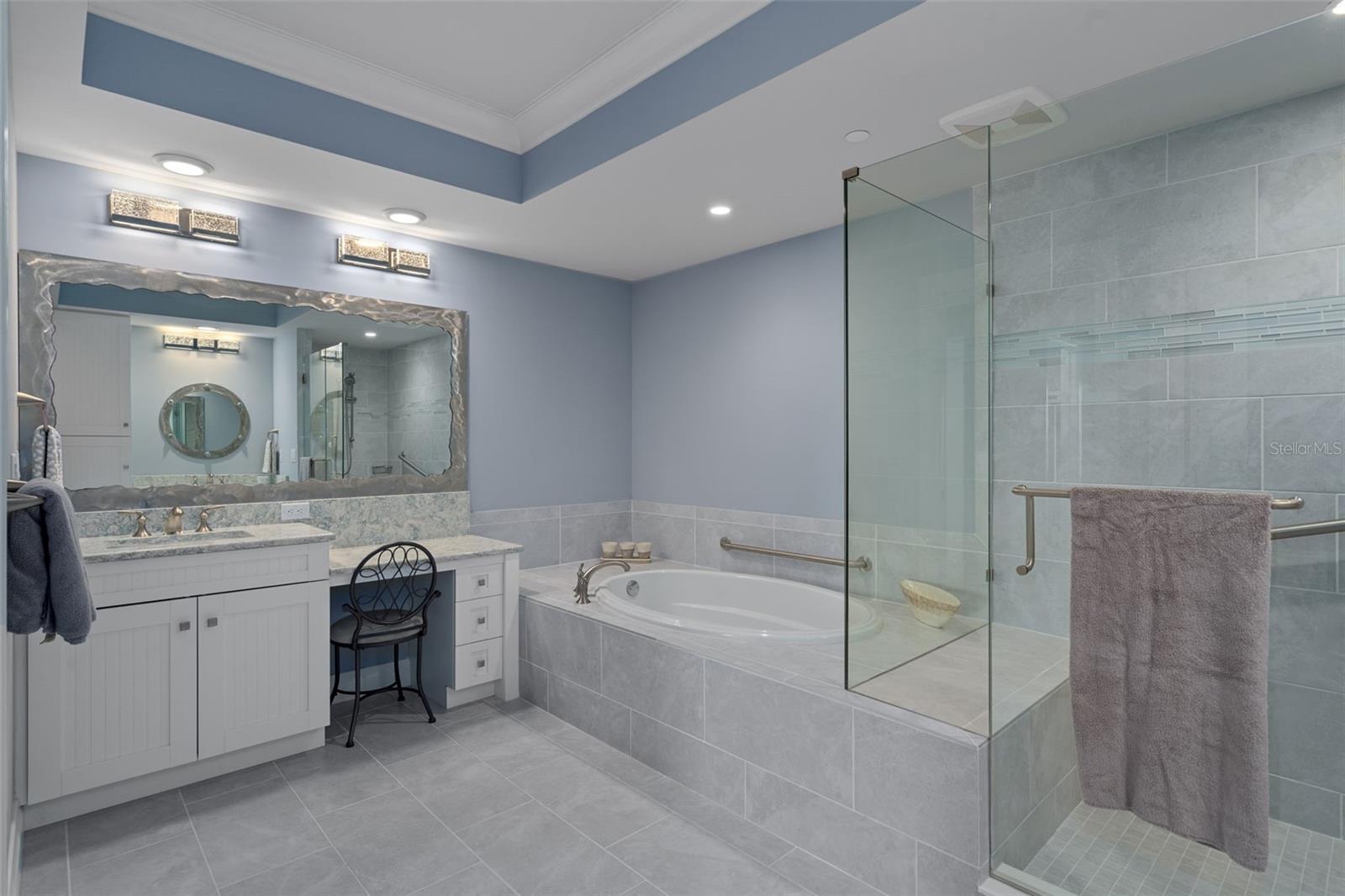 The primary suite bath features dual vanities with custom steel framed mirrors, soaking tub and large walk-in shower.