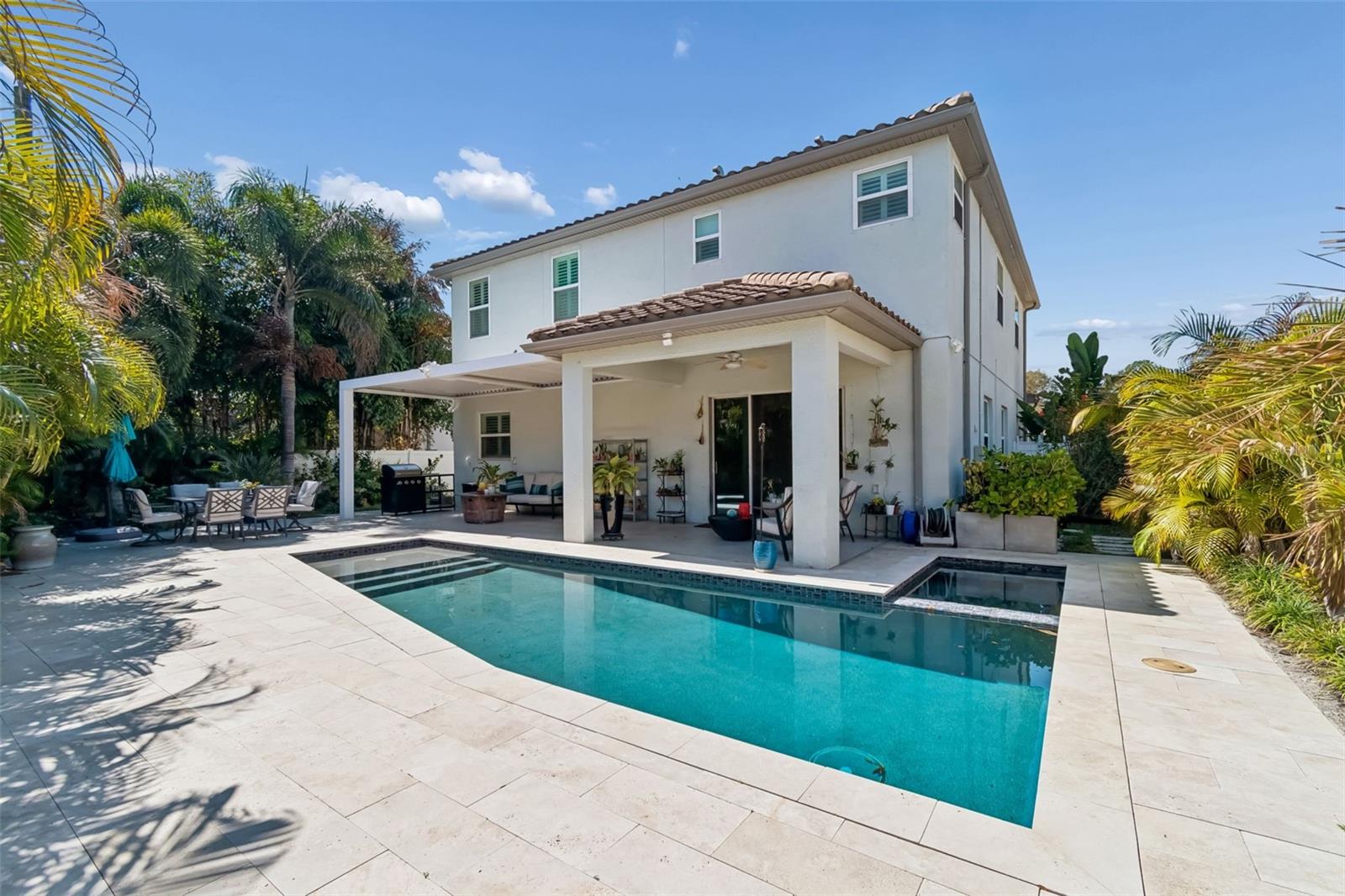 Private tropical backyard with sparkling pool and covered lanai.