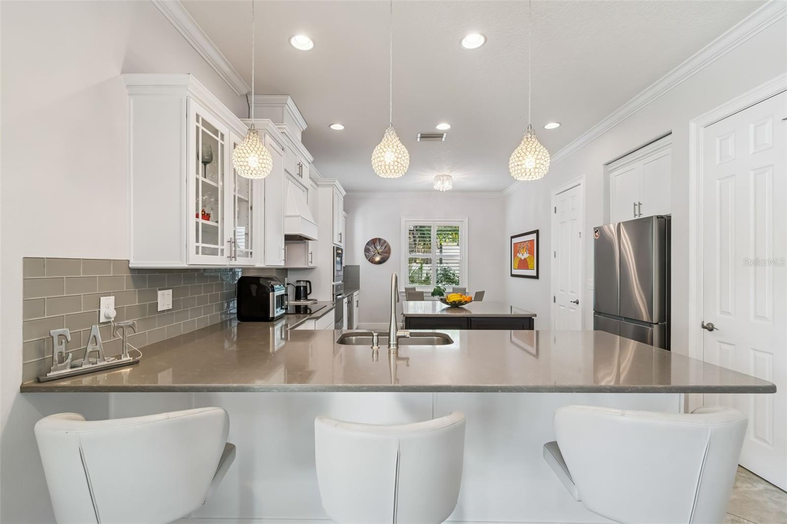 Bright gourmet kitchen with quartz island and elegant pendant lighting.