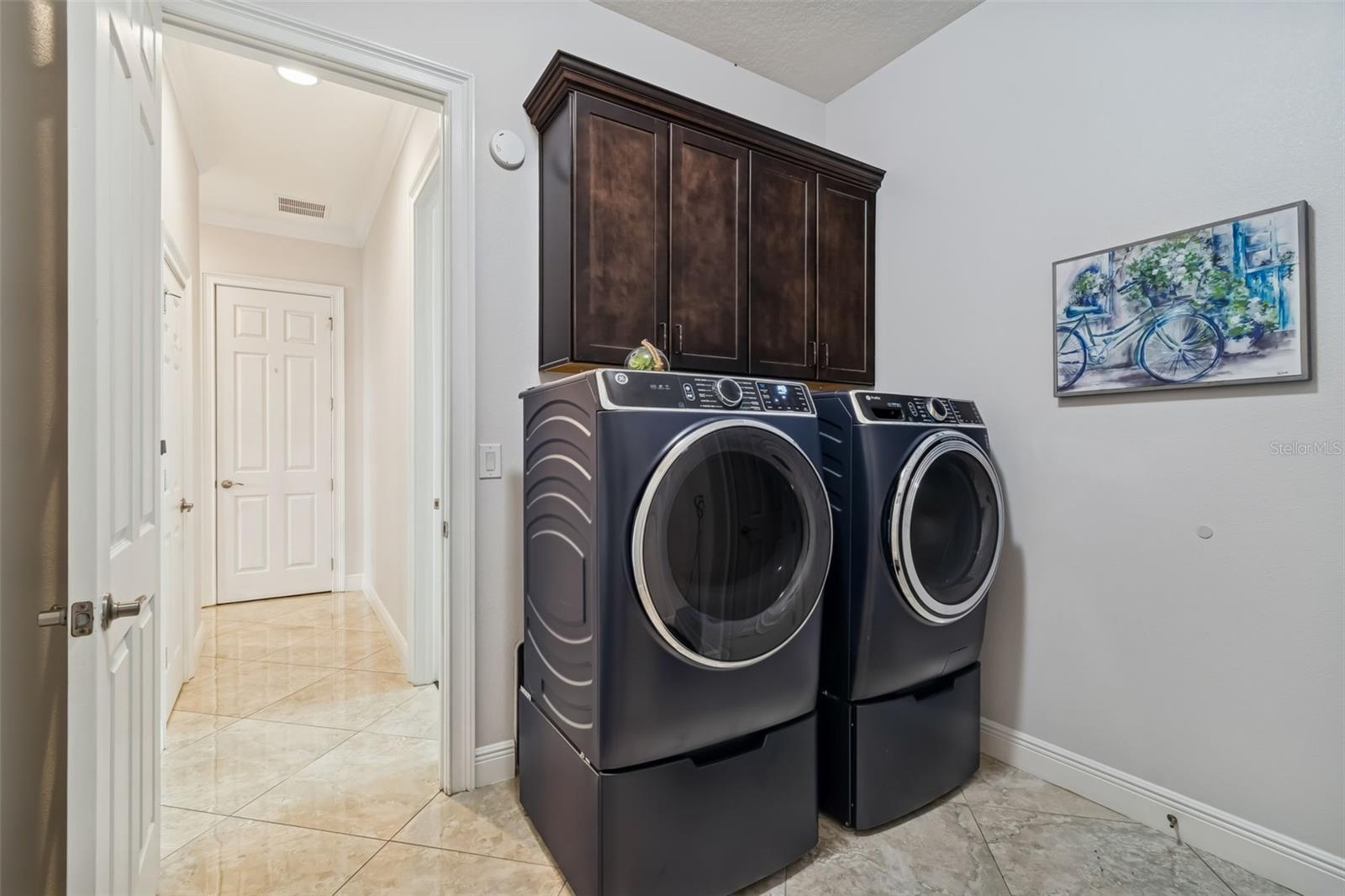 Modern laundry room with front-load washer, dryer, and storage.