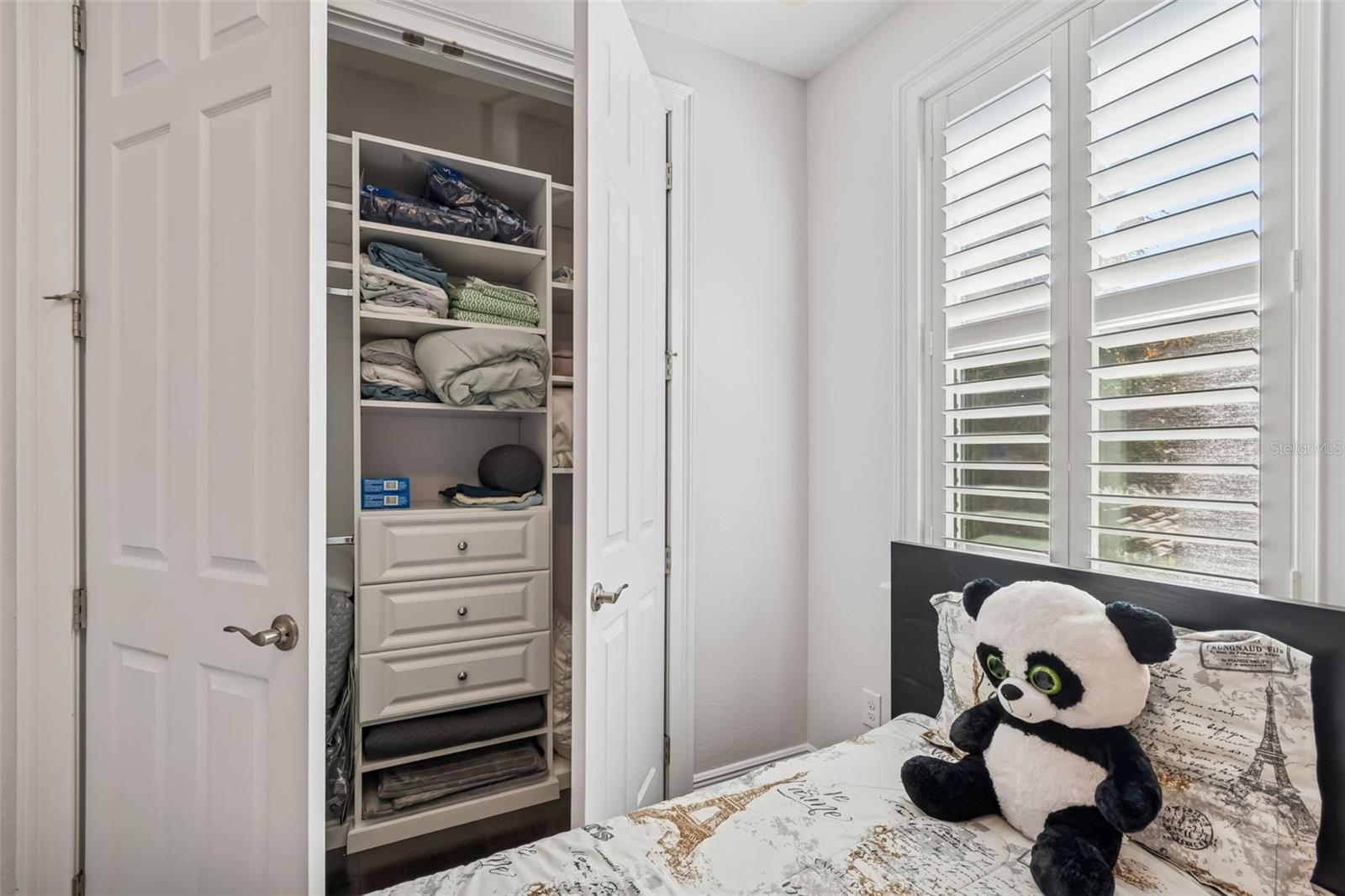 Organized closet with built-in drawers and shelving.