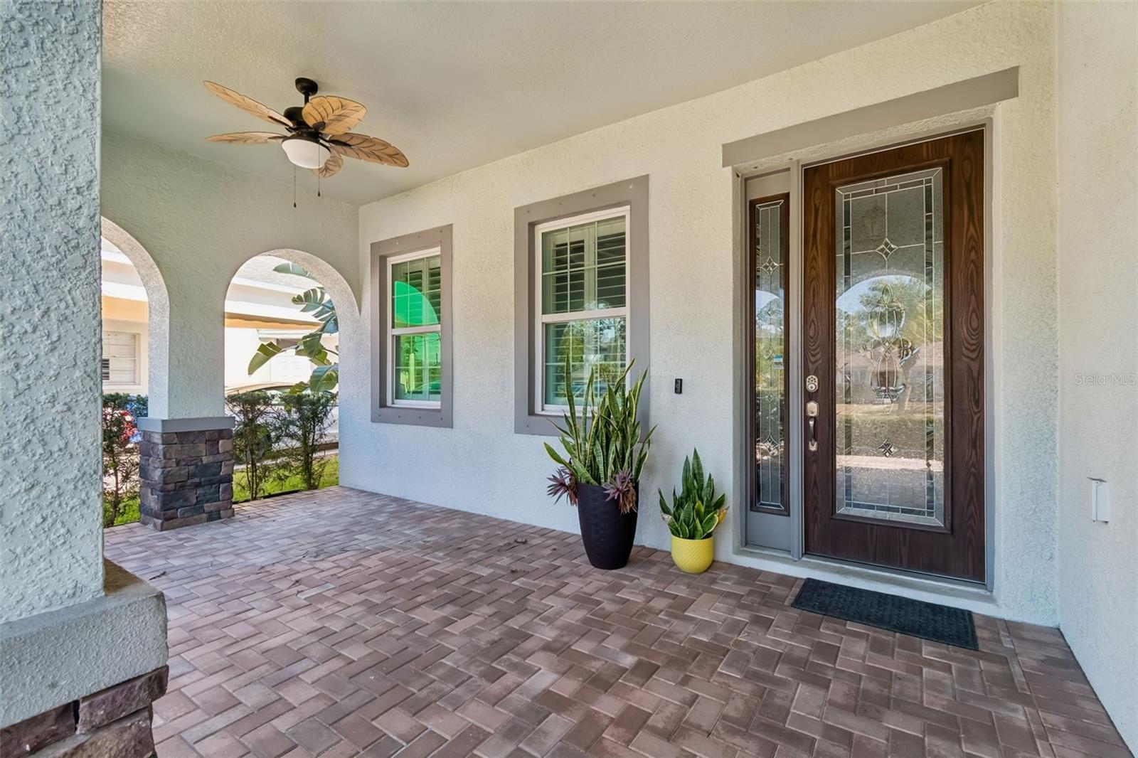 Inviting covered porch with arches and beautiful glass entry door.