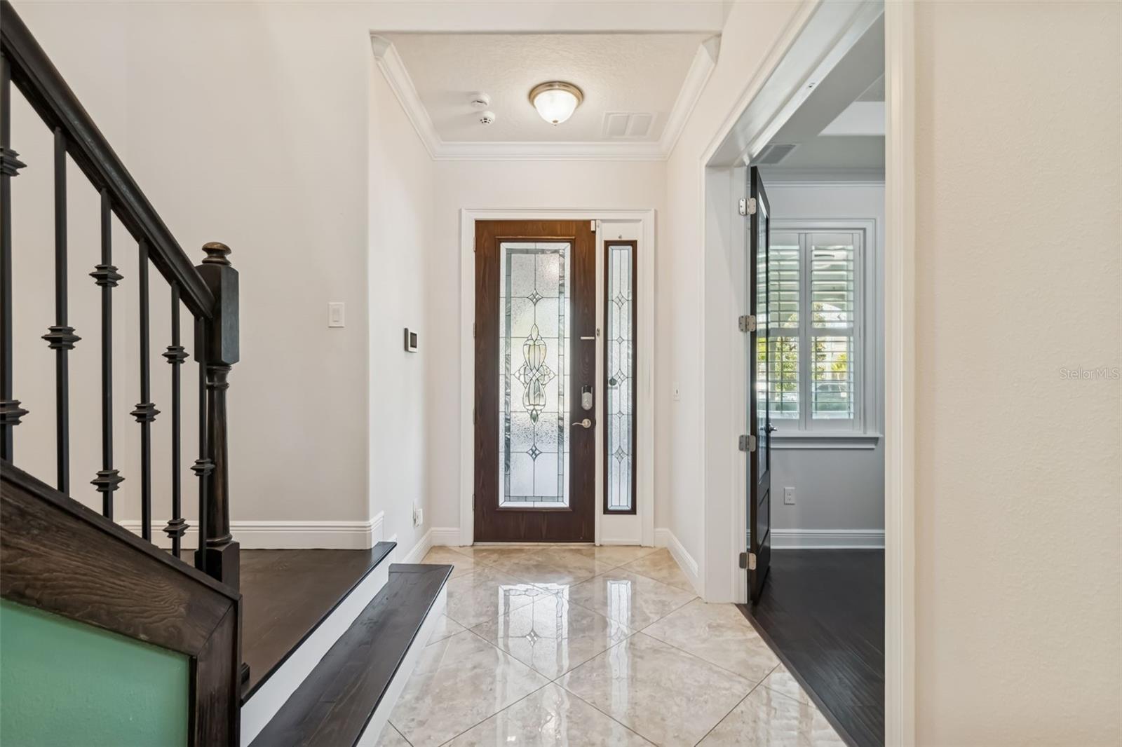 Elegant foyer with polished tile floors and decorative glass front door.
