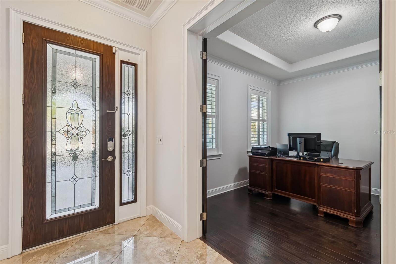 Welcoming foyer with decorative glass door and private office.