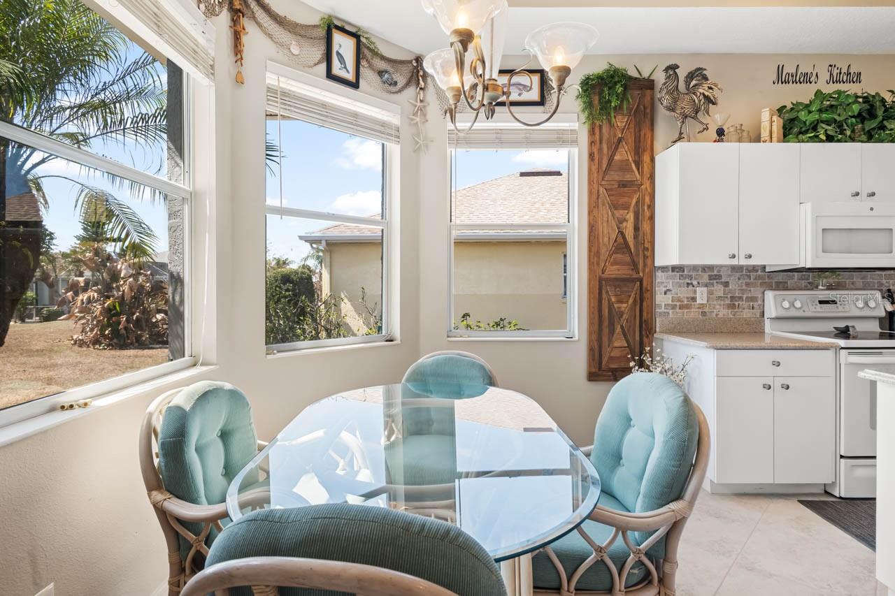 Sun-drenched breakfast nook located just off the kitchen, featuring large windows with bright, open views. This charming dining space is perfect for casual meals and is highlighted by coastal-inspired decor and a seamless connection to the main culinary area