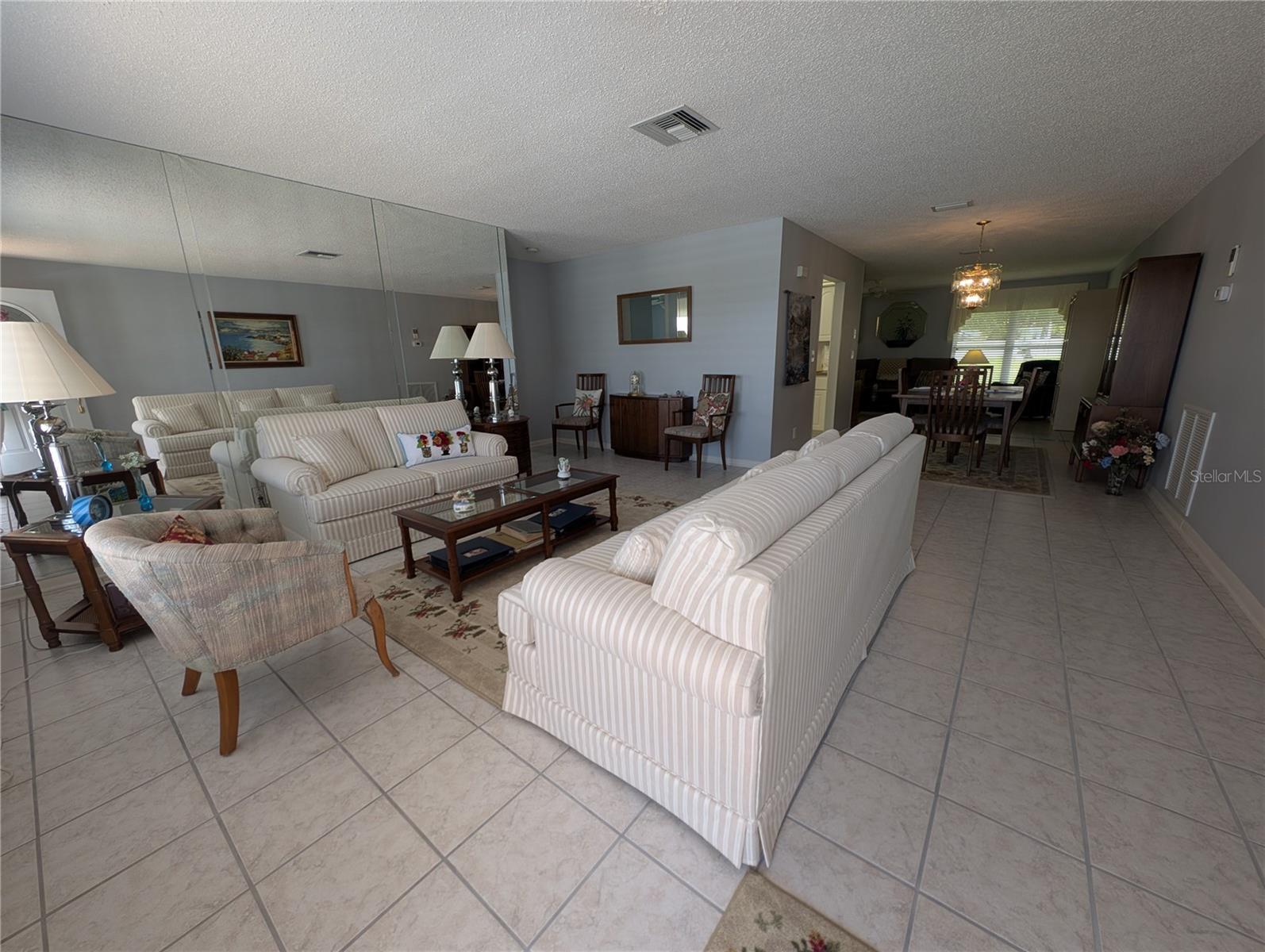 View from front entry thru living room to Dining room then Family room. Split floorplan has guest bedroom to left of living room and primary bedroom down hallway to the right of Florida room.  Kitchen is left of dining room.