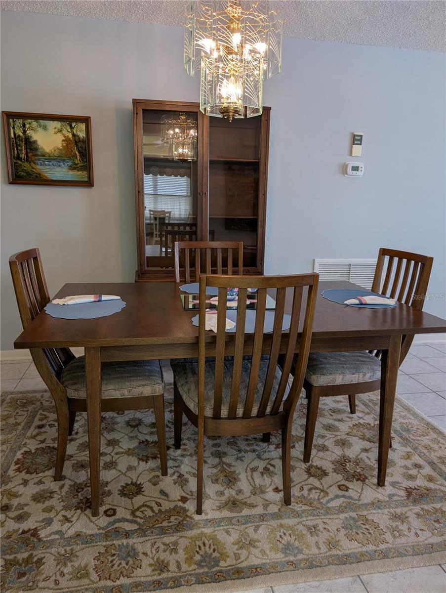 Dining room connects the living room to the Florida room.  Focus of dining room is the sparkling hanging light. Digital thermostat and hygrometer (monitors humidity) on wall to right of hutch.