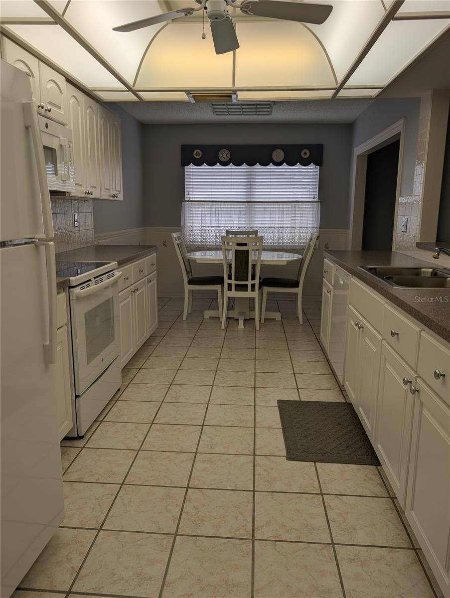 View of well-lit kitchen from dining room to eat in dinette.  Window provides great natural light. Bonus room to right of eat in dinette.  Pass thru window above sink to Florida room is a great convenience when entertaining.