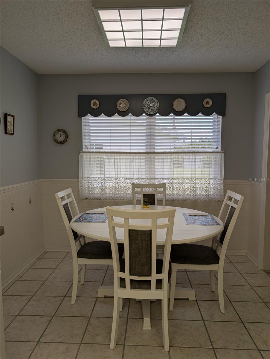 Bright eat in dinette provides comfortable casual dining. Window covering is Venetian blind with wooden valance.  Enjoy morning coffee reflecting while looking out over serene view.