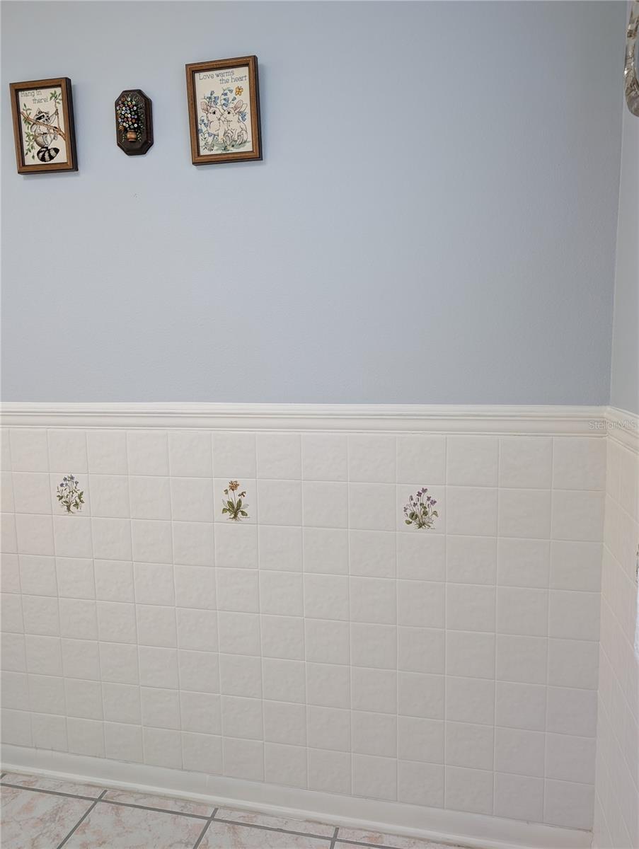 Close up view of white tiled eat in dinette with decorative insert tiles.