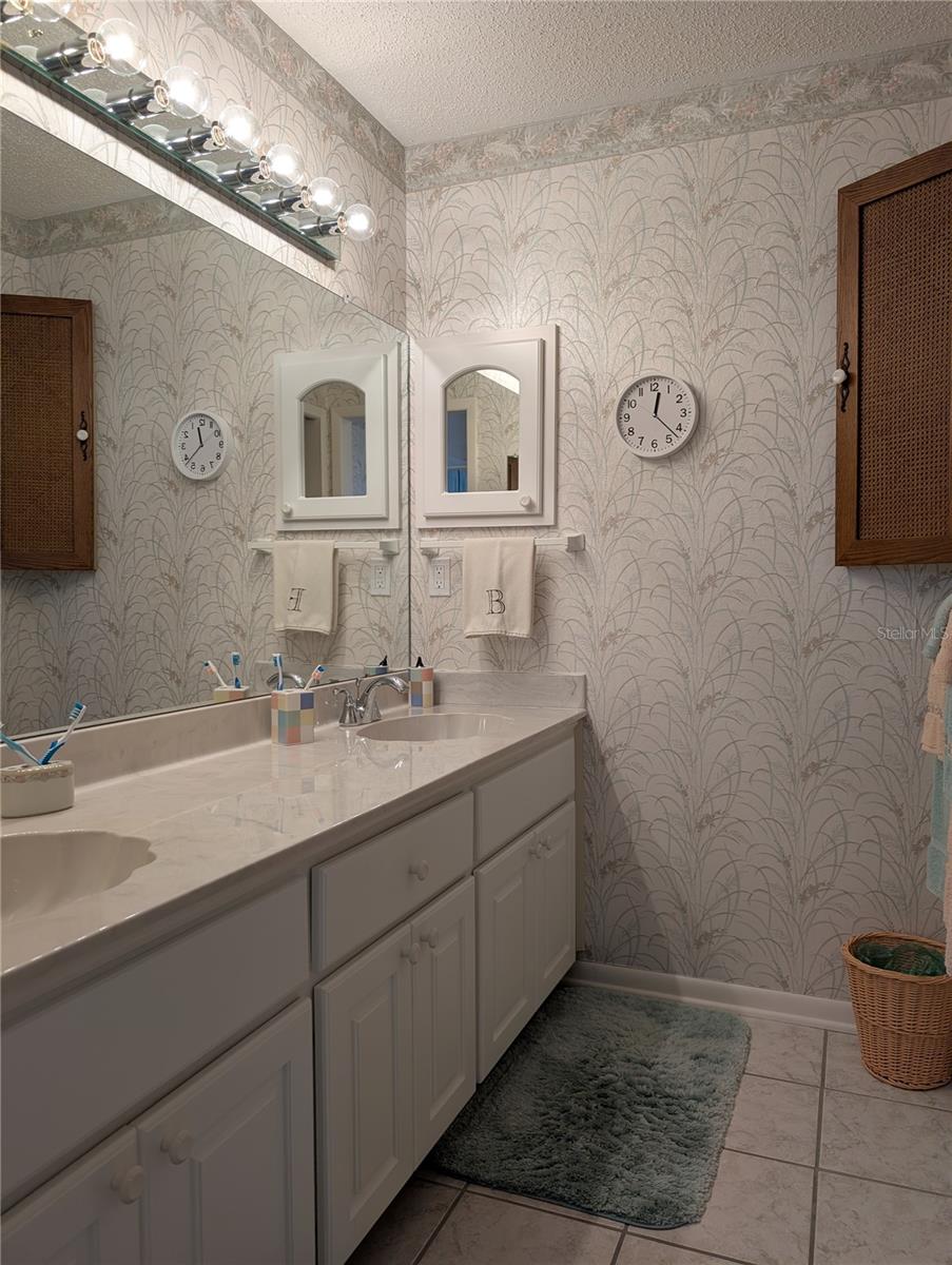 Immaculate ensuite bath features updated white double sink vanity, chrome hardware, faux marble countertop, updated medicine chest and ceramic tile floor.