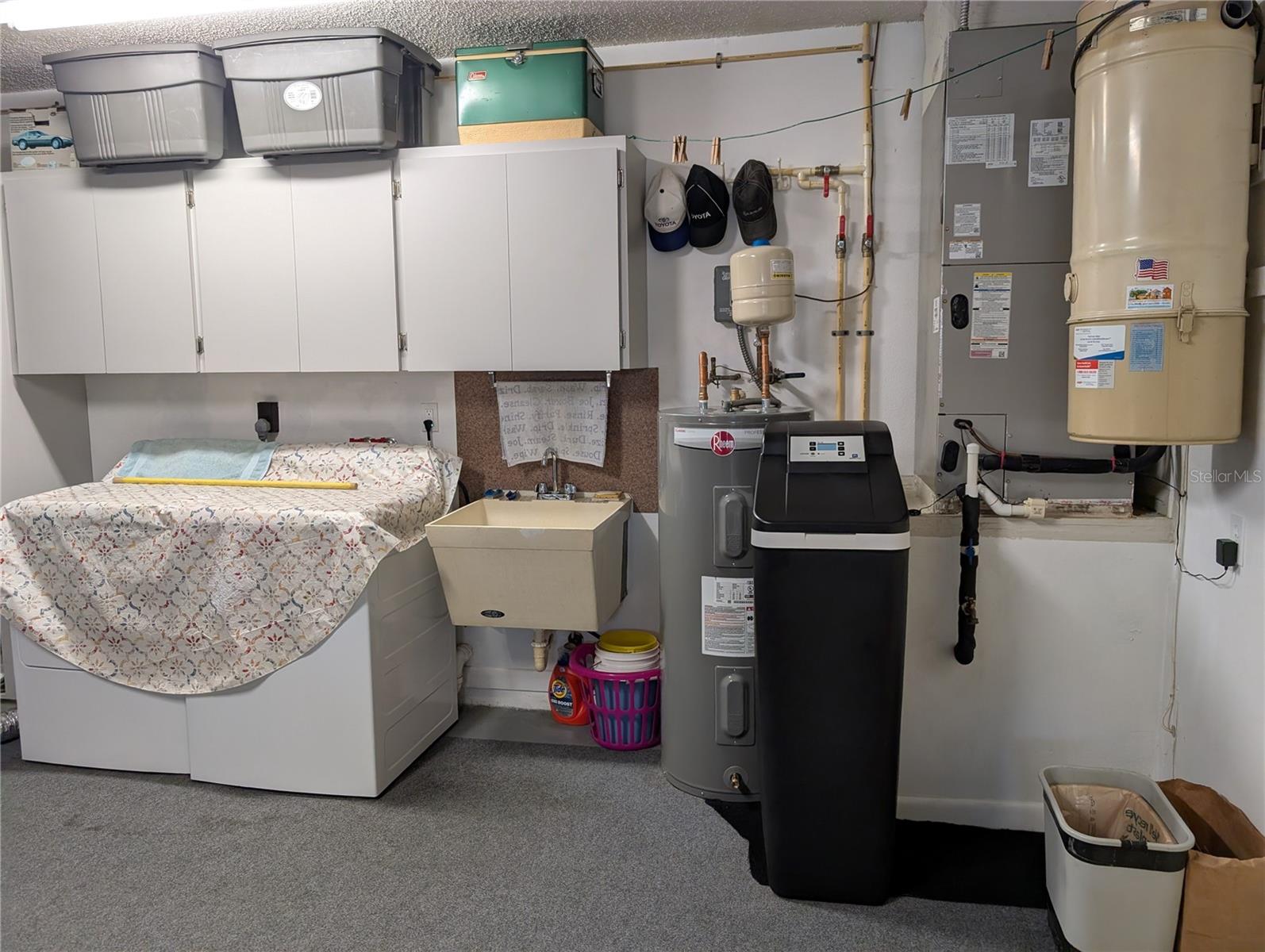Laundry area in garage offers a utility tub, GE washer (2021)/dryer (2017) and storage cabinet.  Also visible is the Rheem water heater (2024), Northstar water softener (2024), Carrier HVAC w/heat pump (2019) and central vacuum system (never used by homeowners).