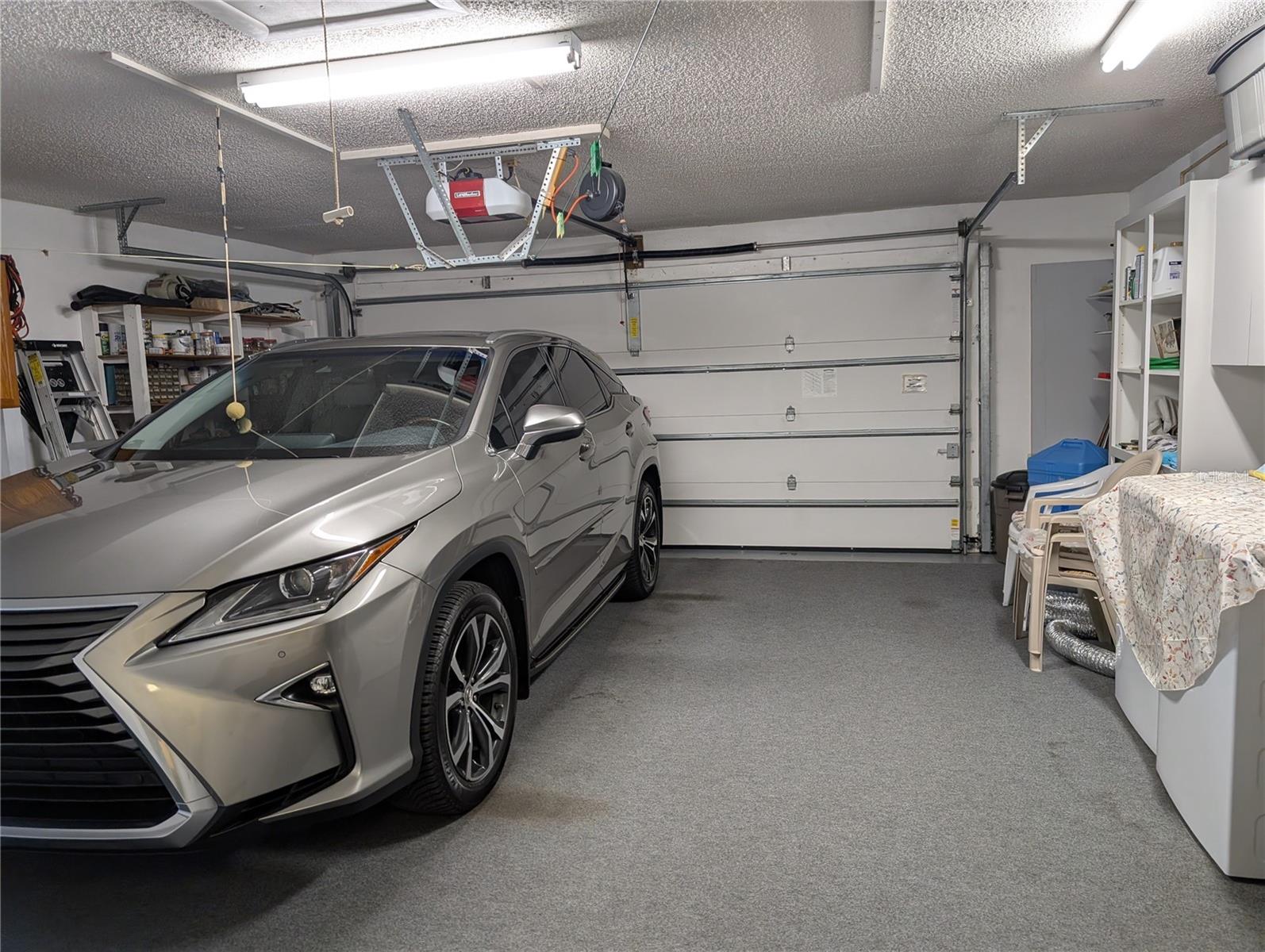 Immaculate Garage features Overhead wind rated door w/reinforcement bar, Liftmaster door motor, pull down ladder for attic access, extra storage, new 200 amp electric panel (2025) and fiberglass exterior door (2015)