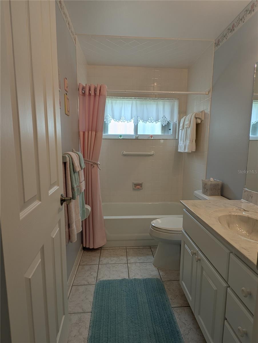 Spotless main bath offers bathtub with shower, faux marble countertop and window for natural light/ventilation.