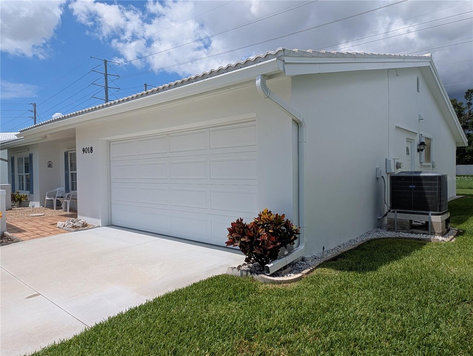 Side view of garage, new cement driveway (2023), Carrier HVAC (2019) and exterior door to side yard.