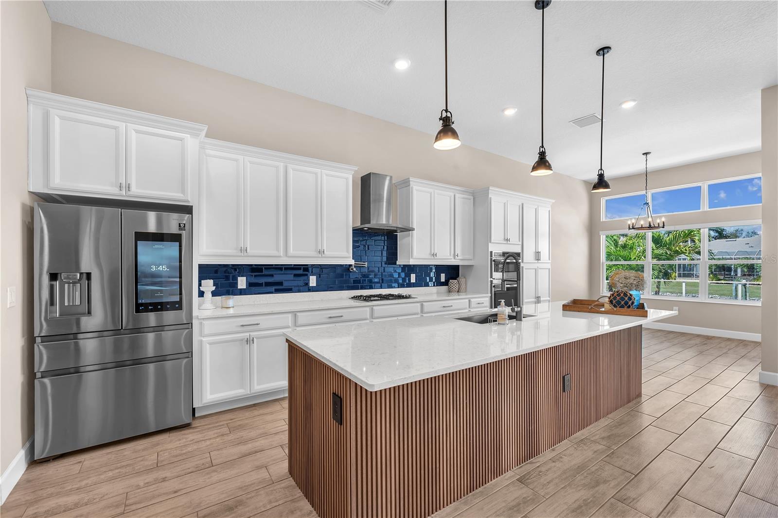 The chef’s kitchen is both beautiful and functional, featuring quartz countertops, stainless steel appliances, a gas cooktop with pot filler, and an oversized island with seating