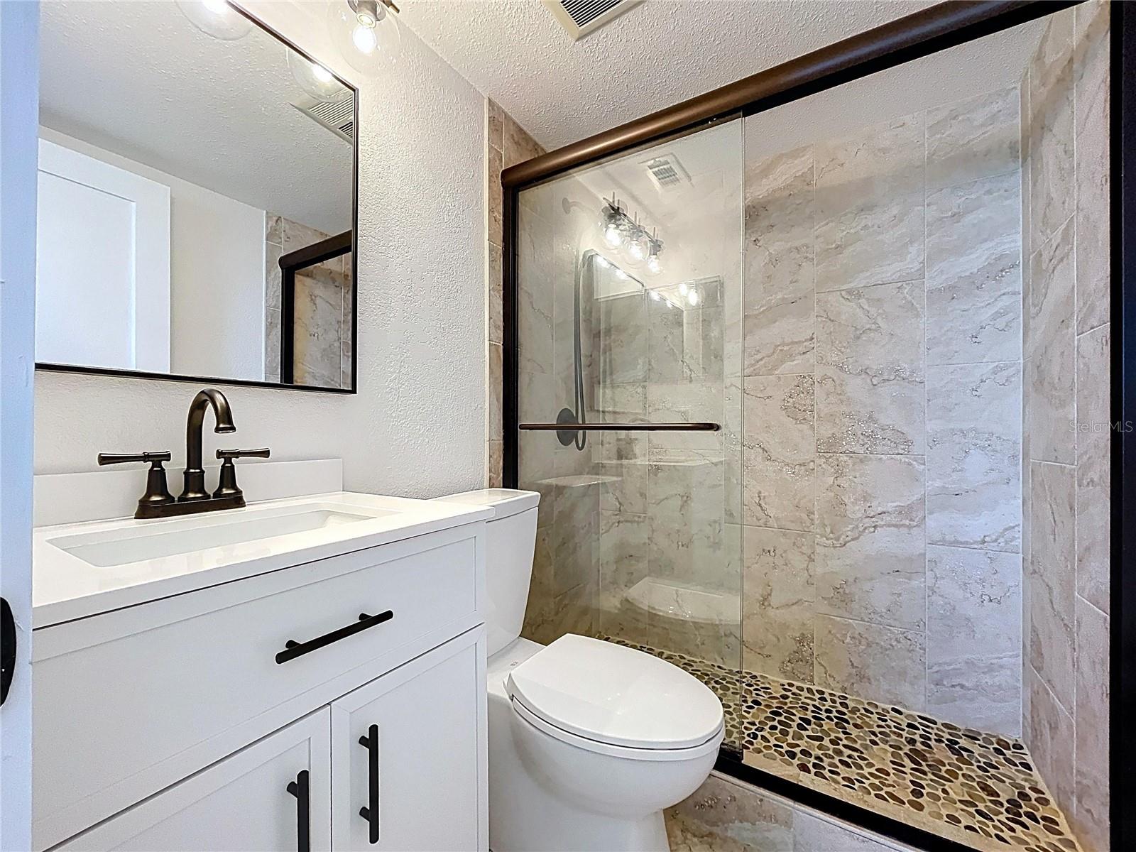 Fully renovated Primary bathroom with walk-in shower and glass shower door.