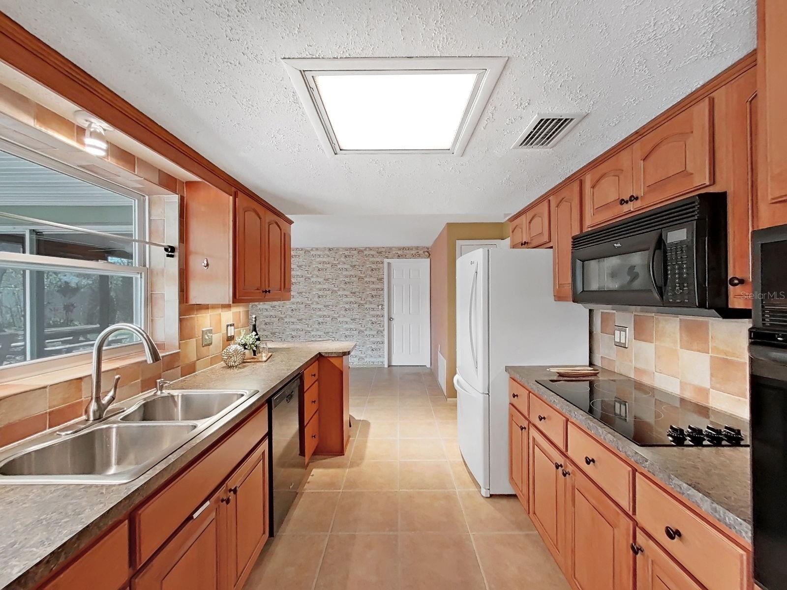 Kitchen with warm wood updated cabinetry, tile backsplash, and ample storage.