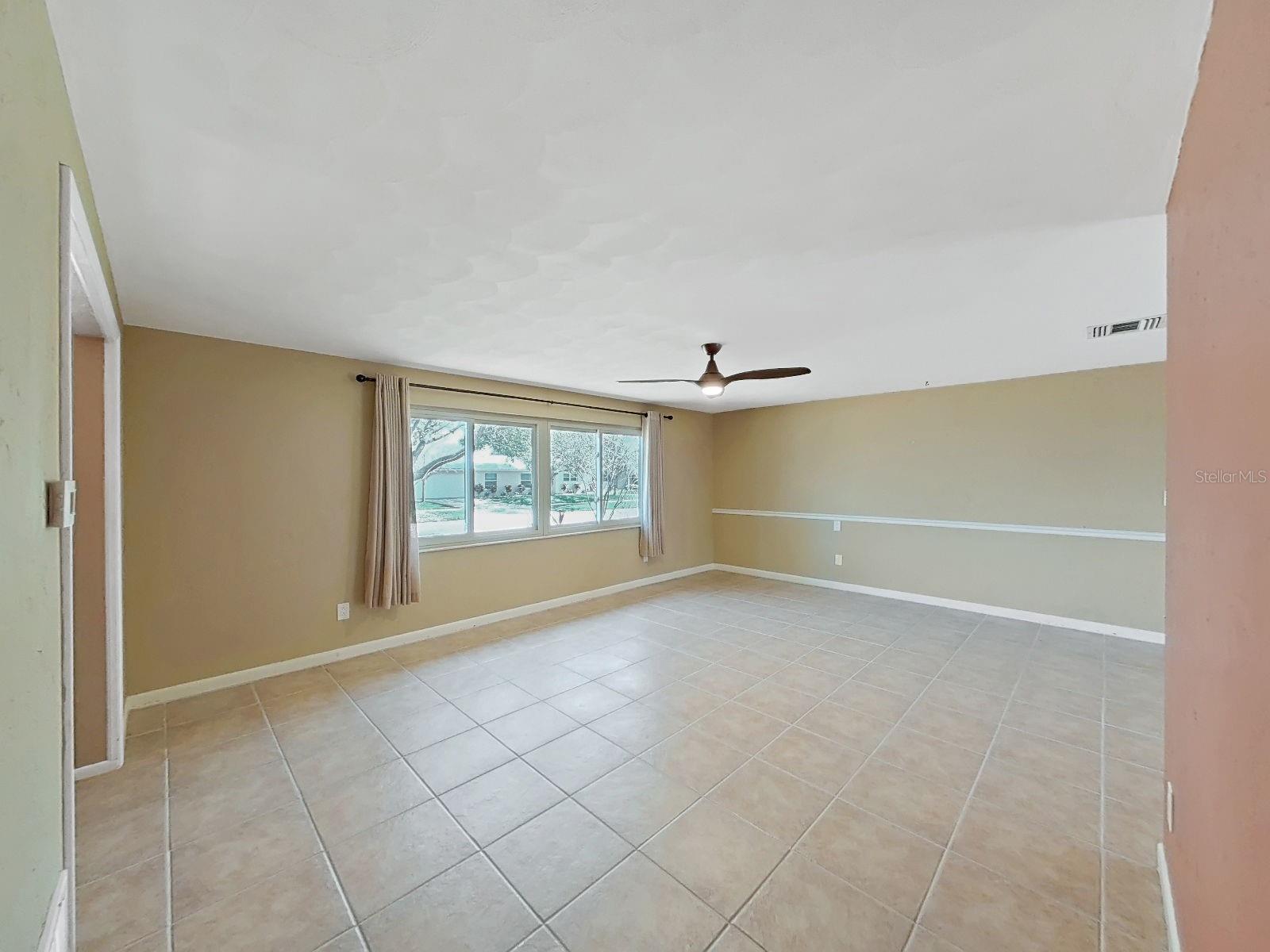 Generously sized living room features neutral tile, ceiling fan, and NEW impact-rated energy-efficient vinyl slider windows.