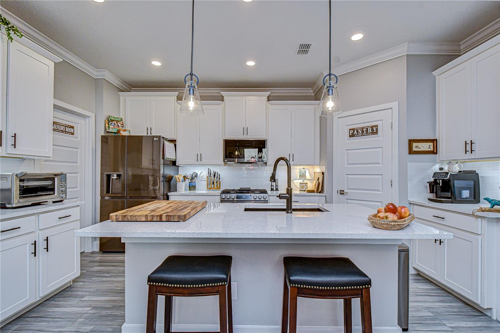 Large center island with deep utility sink, dishwasher, and pendant lighting.