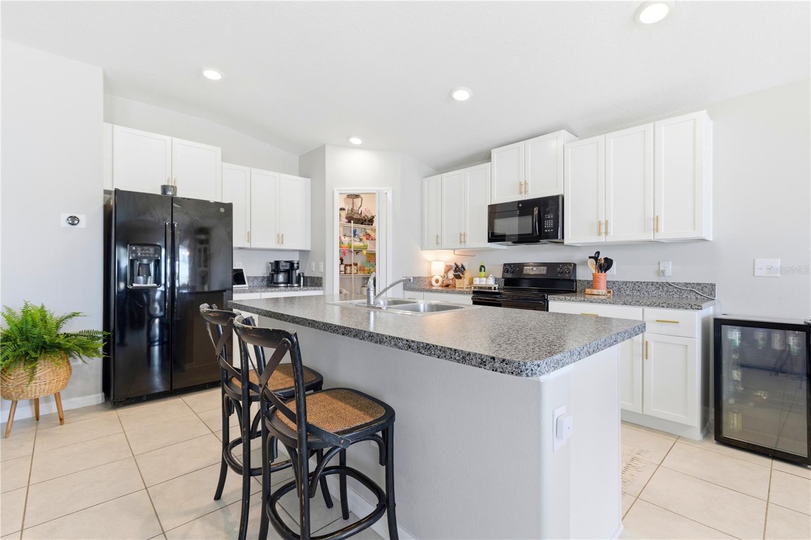 Beautiful kitchen with eat-in space at the bar, pantry and shaker style cabinetry.
